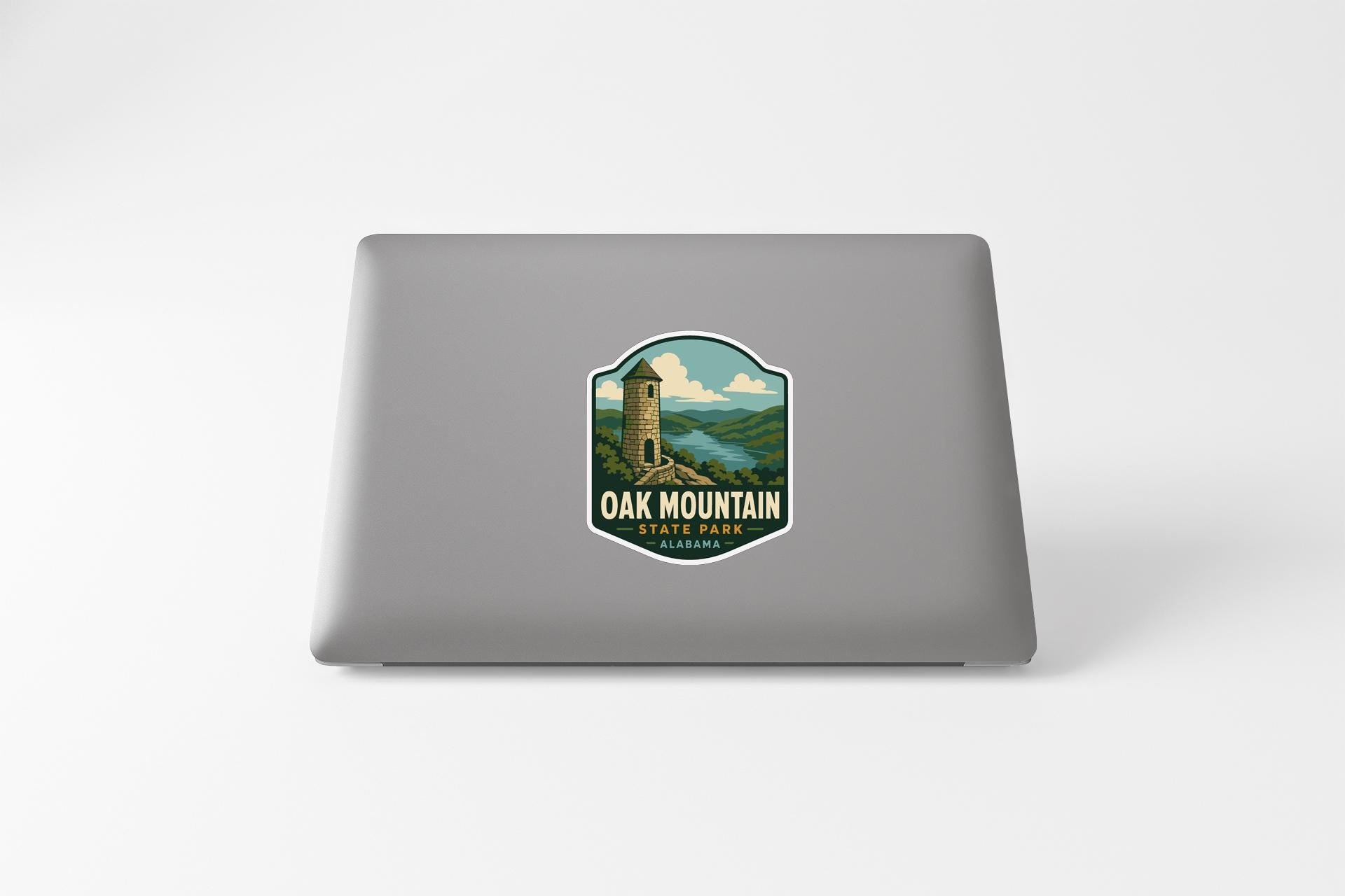 A sticker on the back of a laptop, depicting a scenic landscape with a tower in the background.