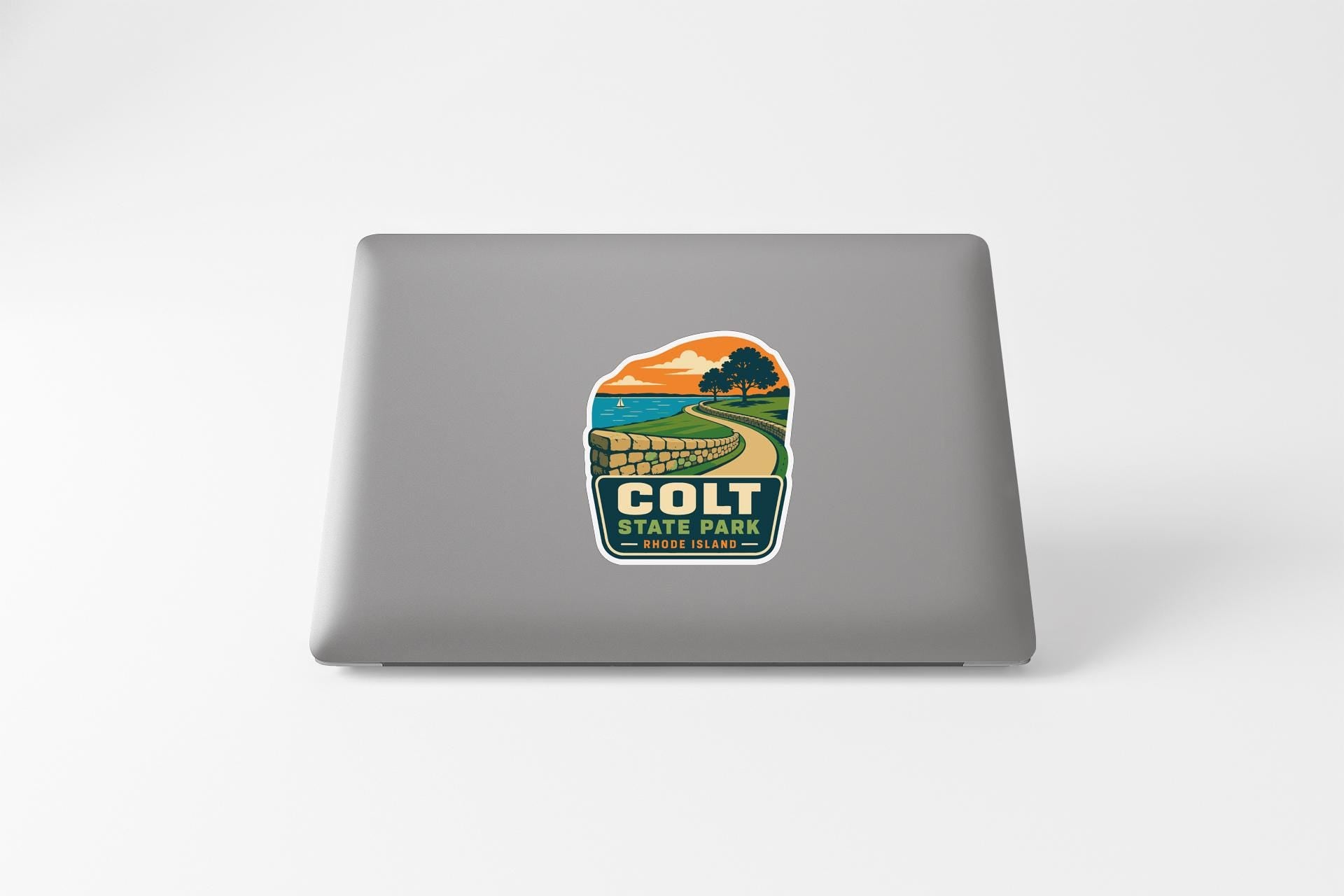 A sticker on the back of a laptop, depicting a scenic landscape with a road leading to a mountain.