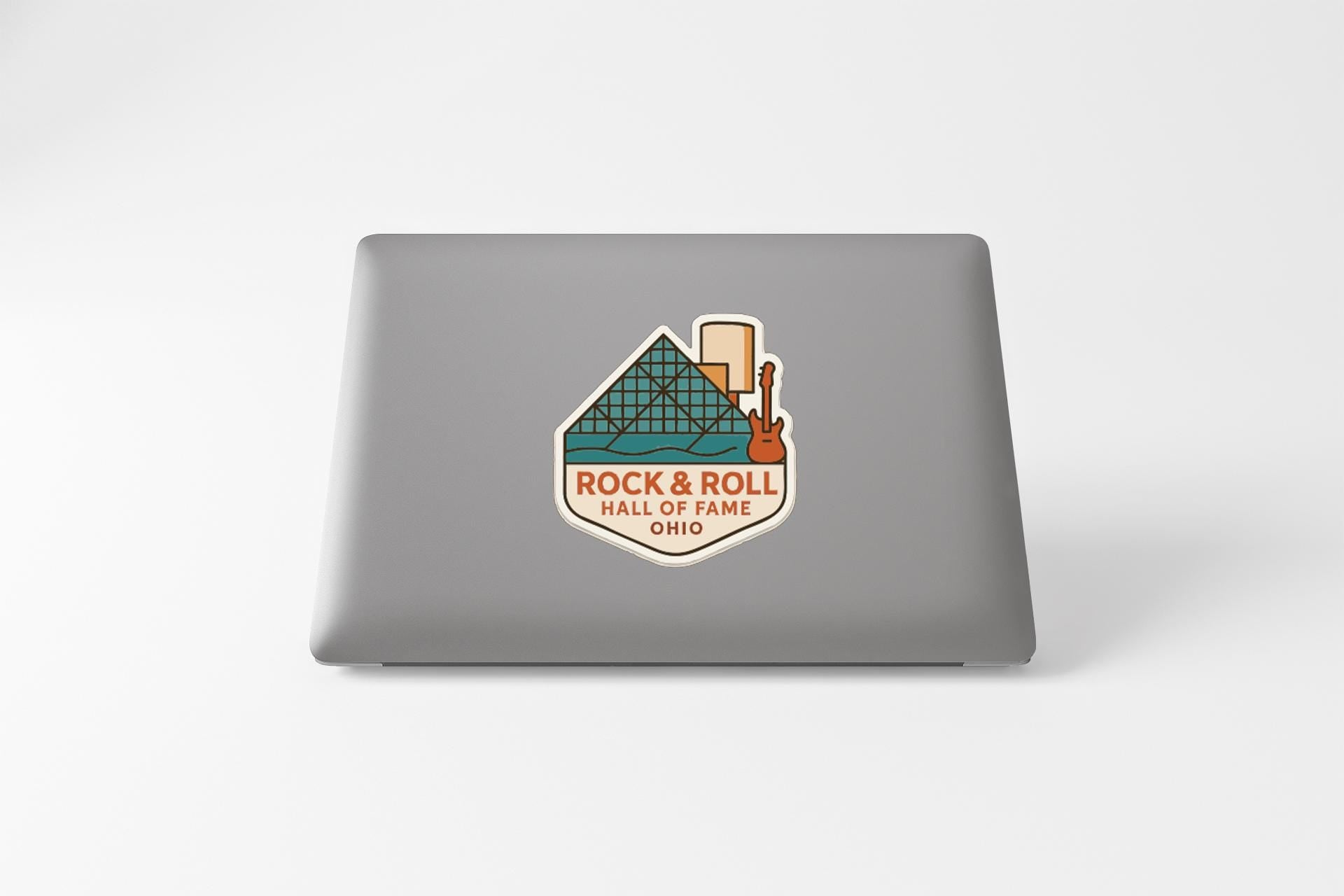 A sticker on the back of a laptop that says "ROCK & ROLL HALL OF FAME OHIO".
