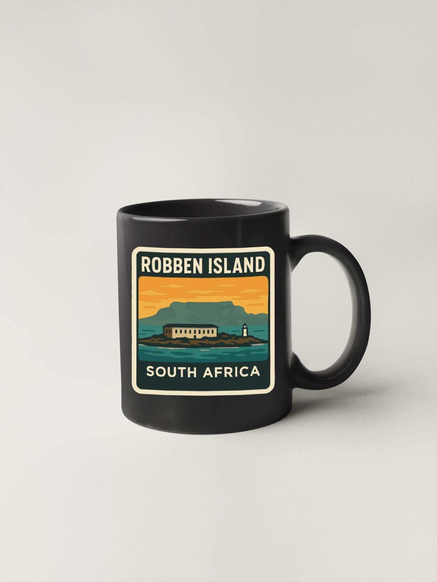 A black coffee mug with a graphic design depicting Robben Island, a famous landmark in South Africa.