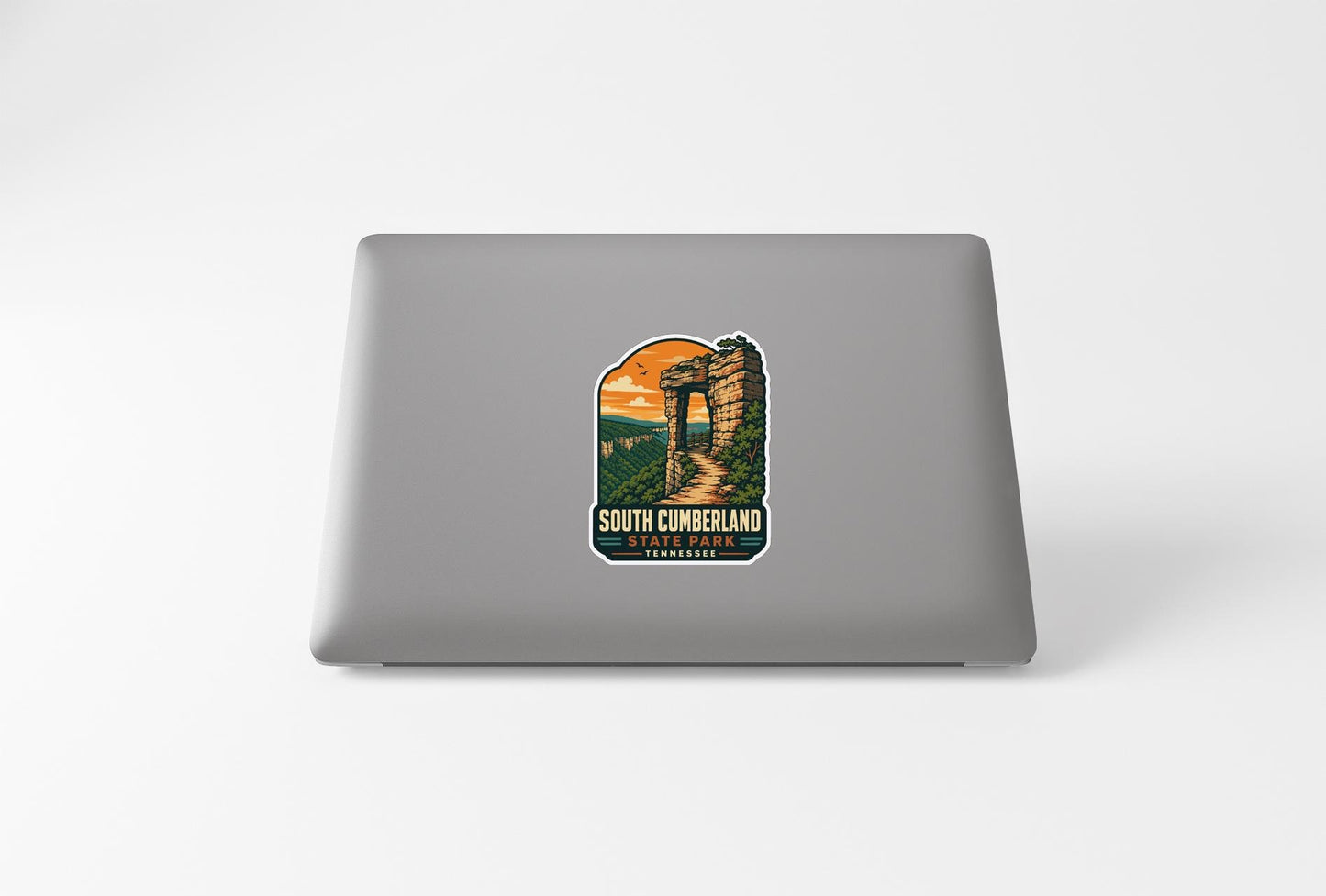 A sticker depicting a castle or fortification with a scenic landscape in the background, placed on the back of a laptop computer.
