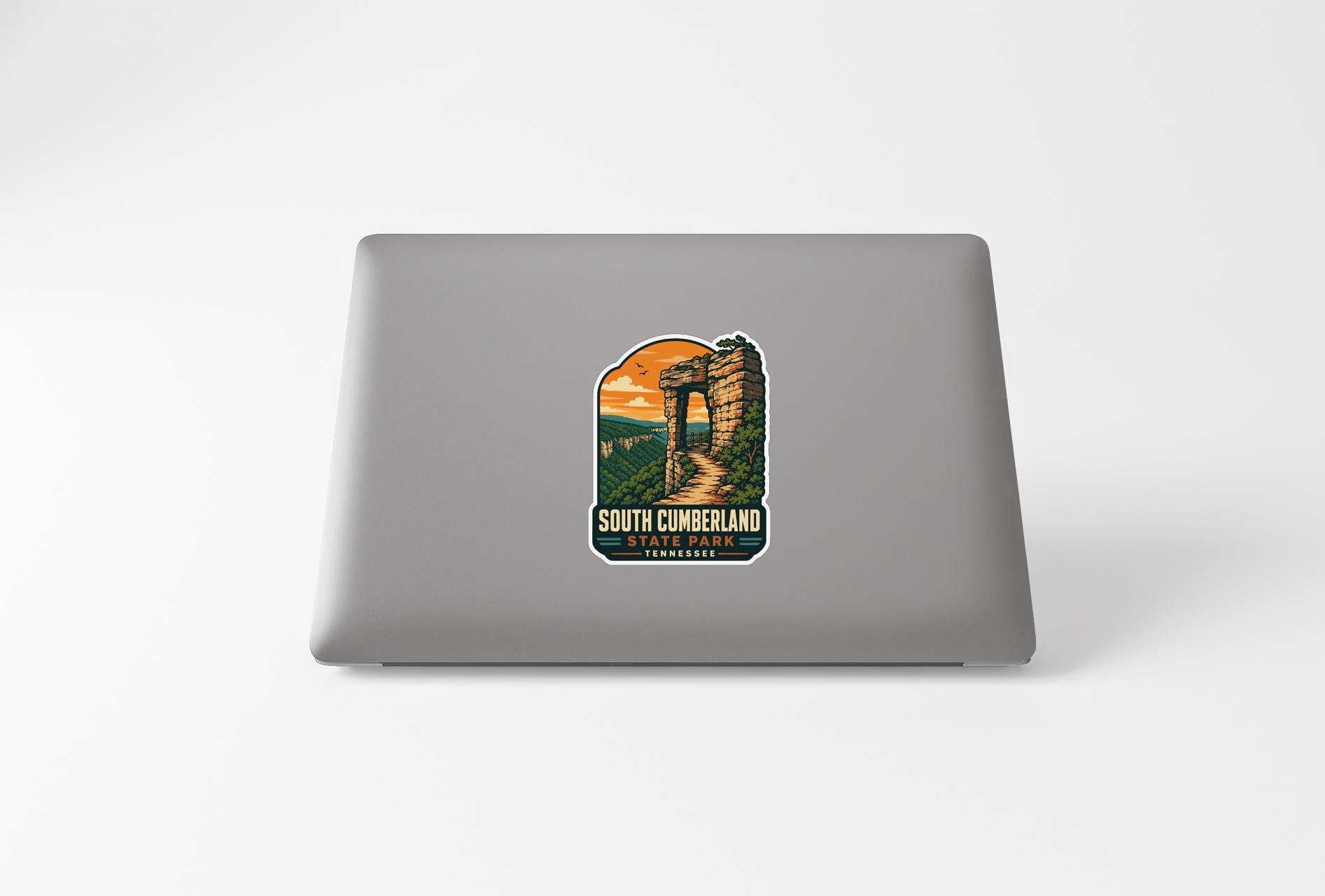 A sticker depicting a castle or fortification with a scenic landscape in the background, placed on the back of a laptop computer.