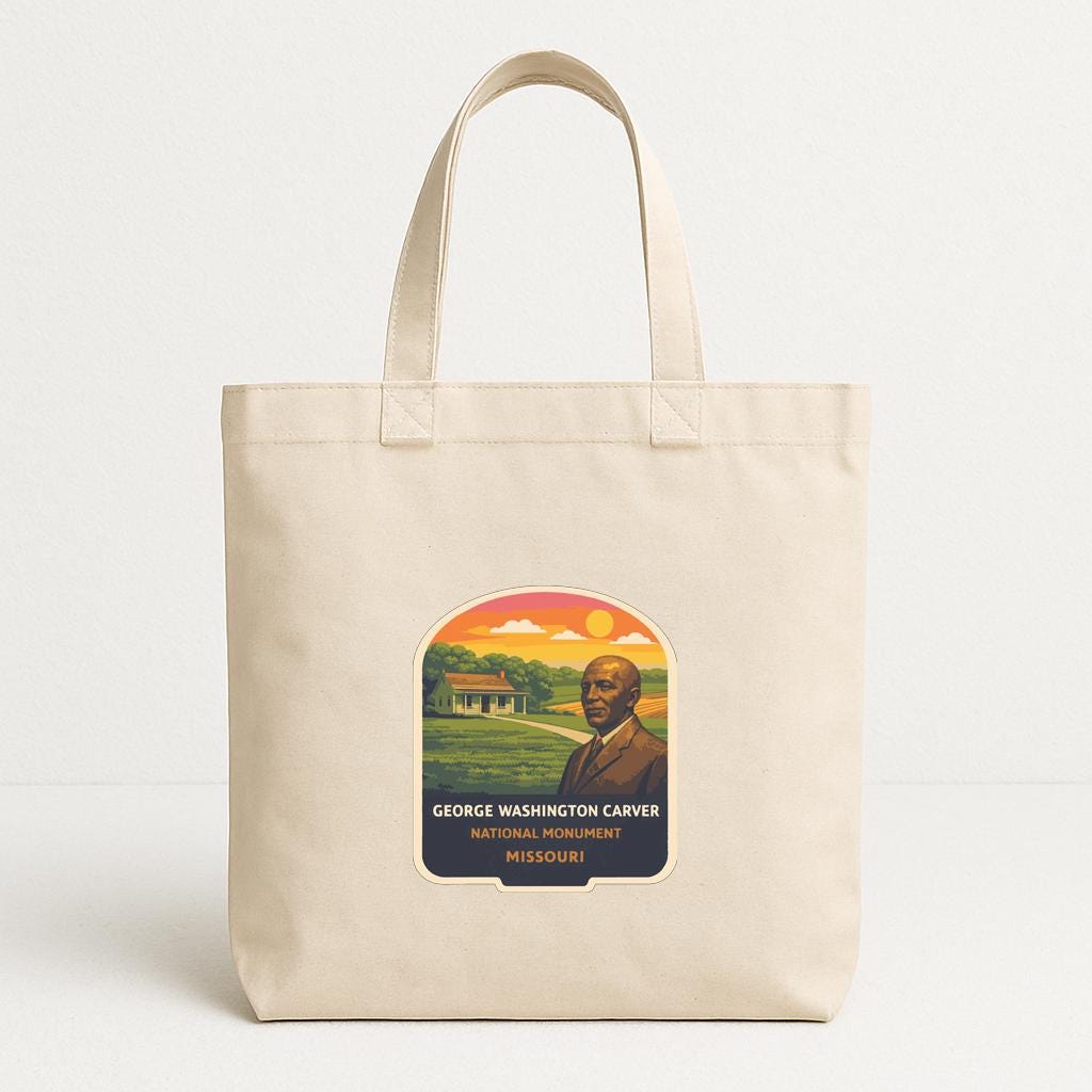 A beige tote bag with a printed label that features an illustration of a historical monument and the text "GEORGE WASHINGTON CARVER NATIONAL MONUMENT MISSOURI".