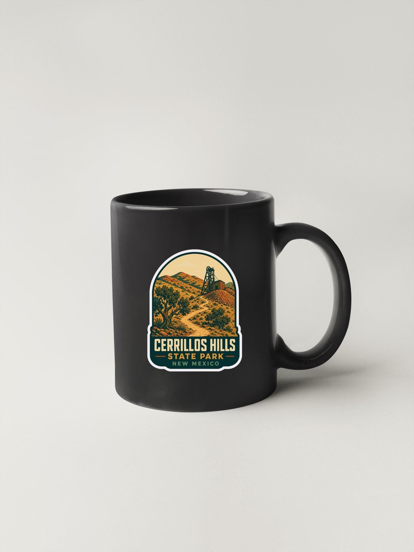 A black coffee mug with a label that says "CERRILLOS HILLS STATE PARK".