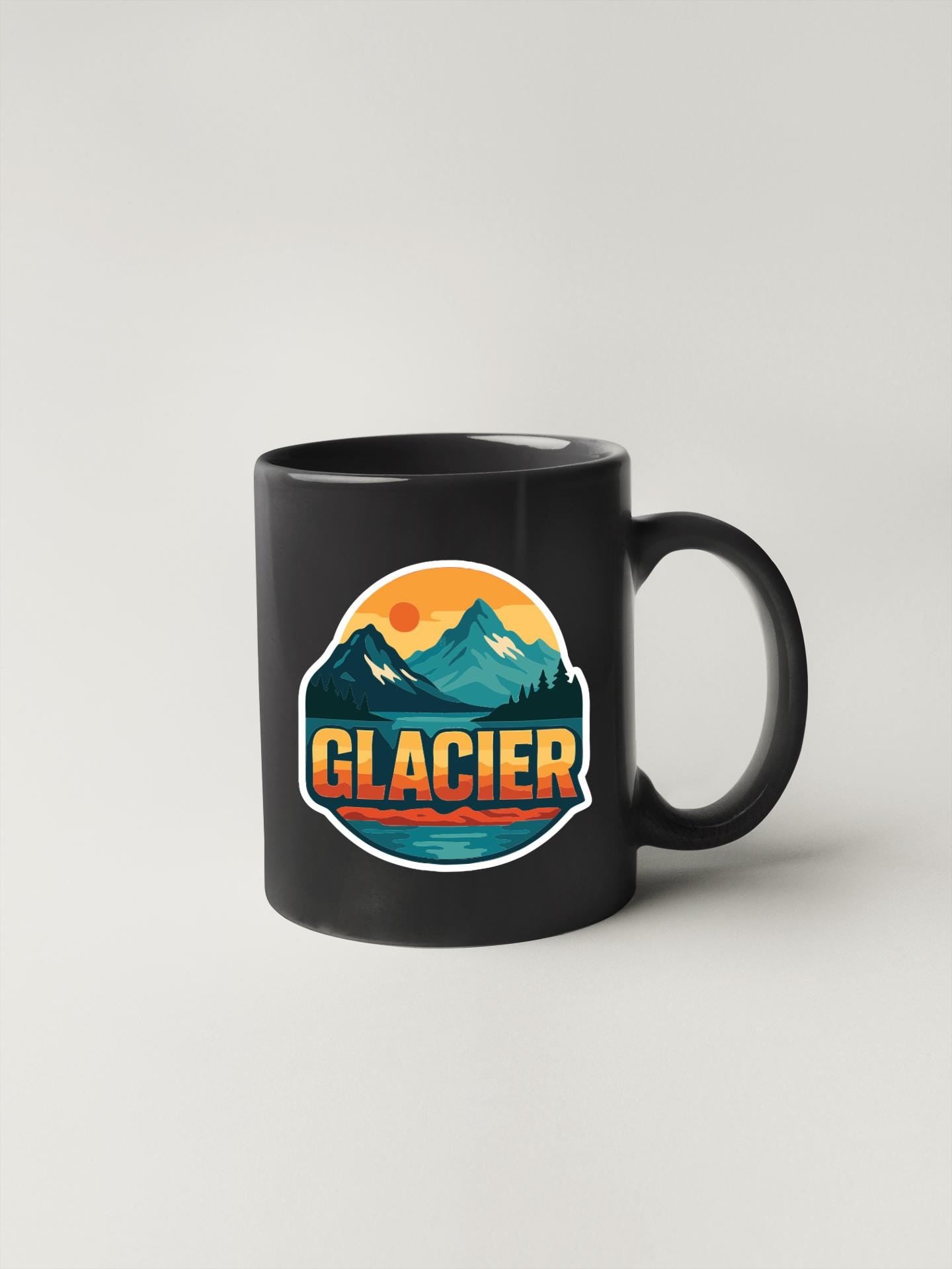 A black coffee mug with a graphic design featuring mountains, a sunset, and the word "GLACIER" written on it.