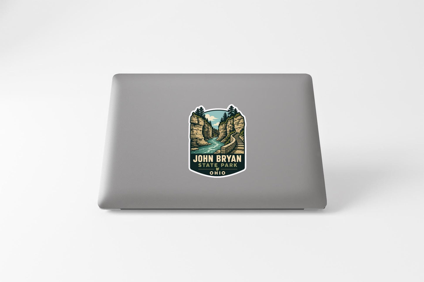 A sticker on the back of a laptop, depicting a scenic landscape with a river and mountains.