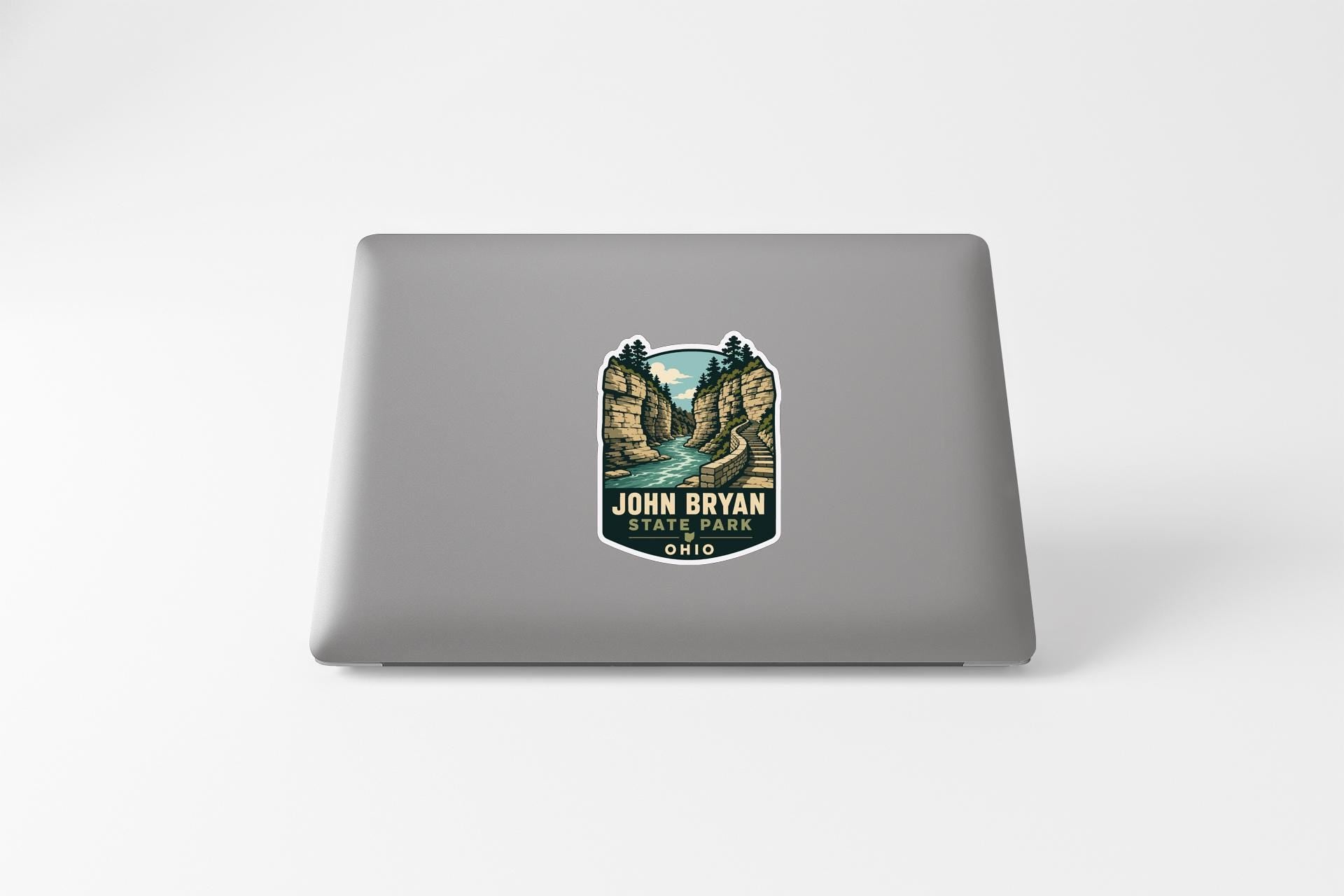 A sticker on the back of a laptop, depicting a scenic landscape with a river and mountains.