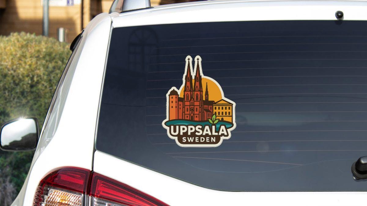 A sticker on the rear window of a car, depicting a city skyline with a church spire.