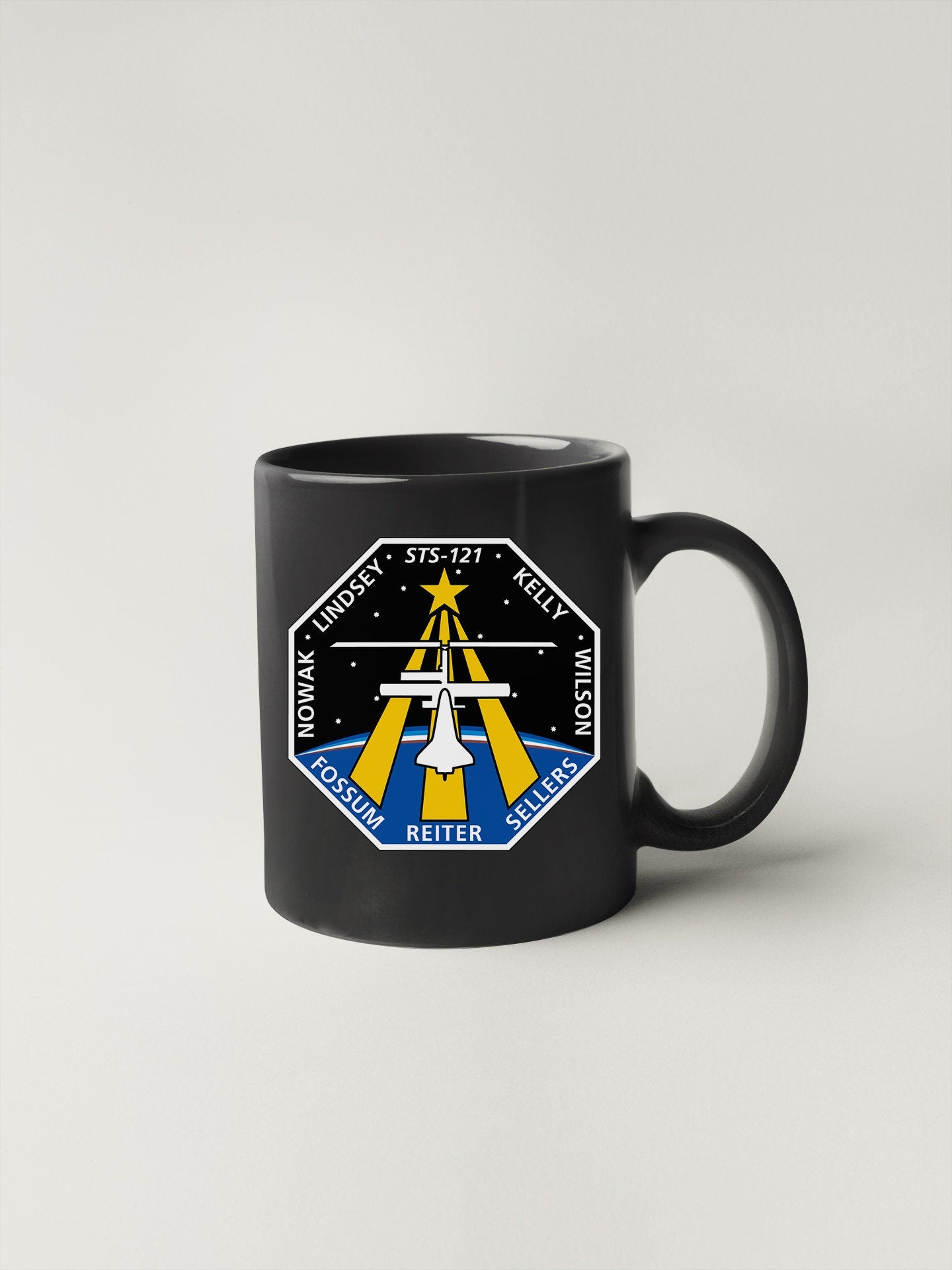 a black coffee mug with a nasa emblem on it