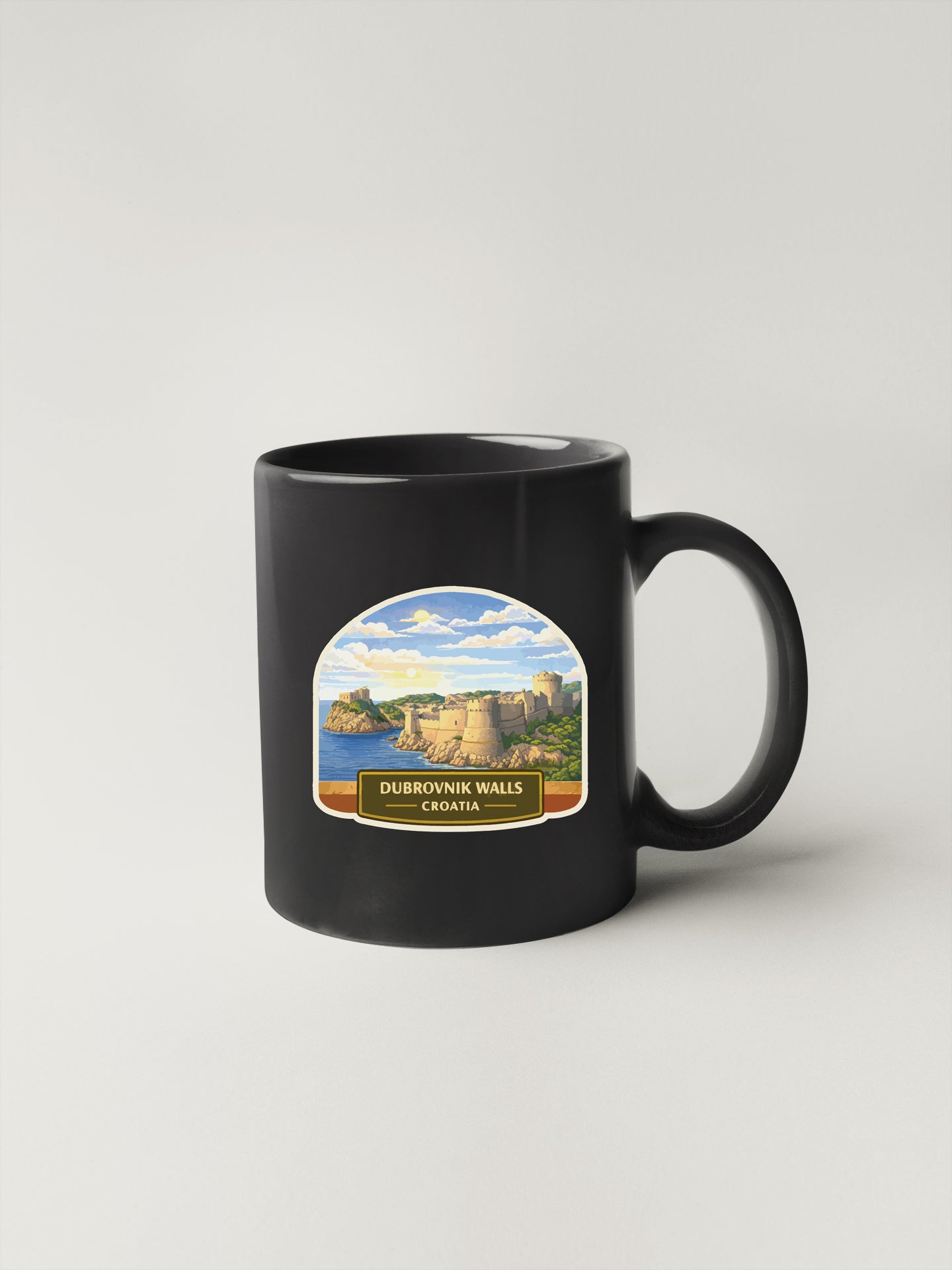 A black coffee mug with a label depicting Dubrovnik, Croatia, featuring a scenic landscape with a castle and a body of water.
