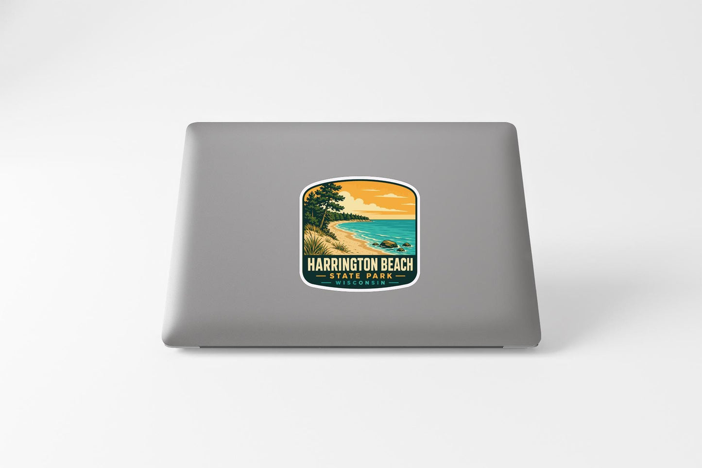 A sticker on the back of a laptop, depicting a scenic beach landscape with a sunset over the water.