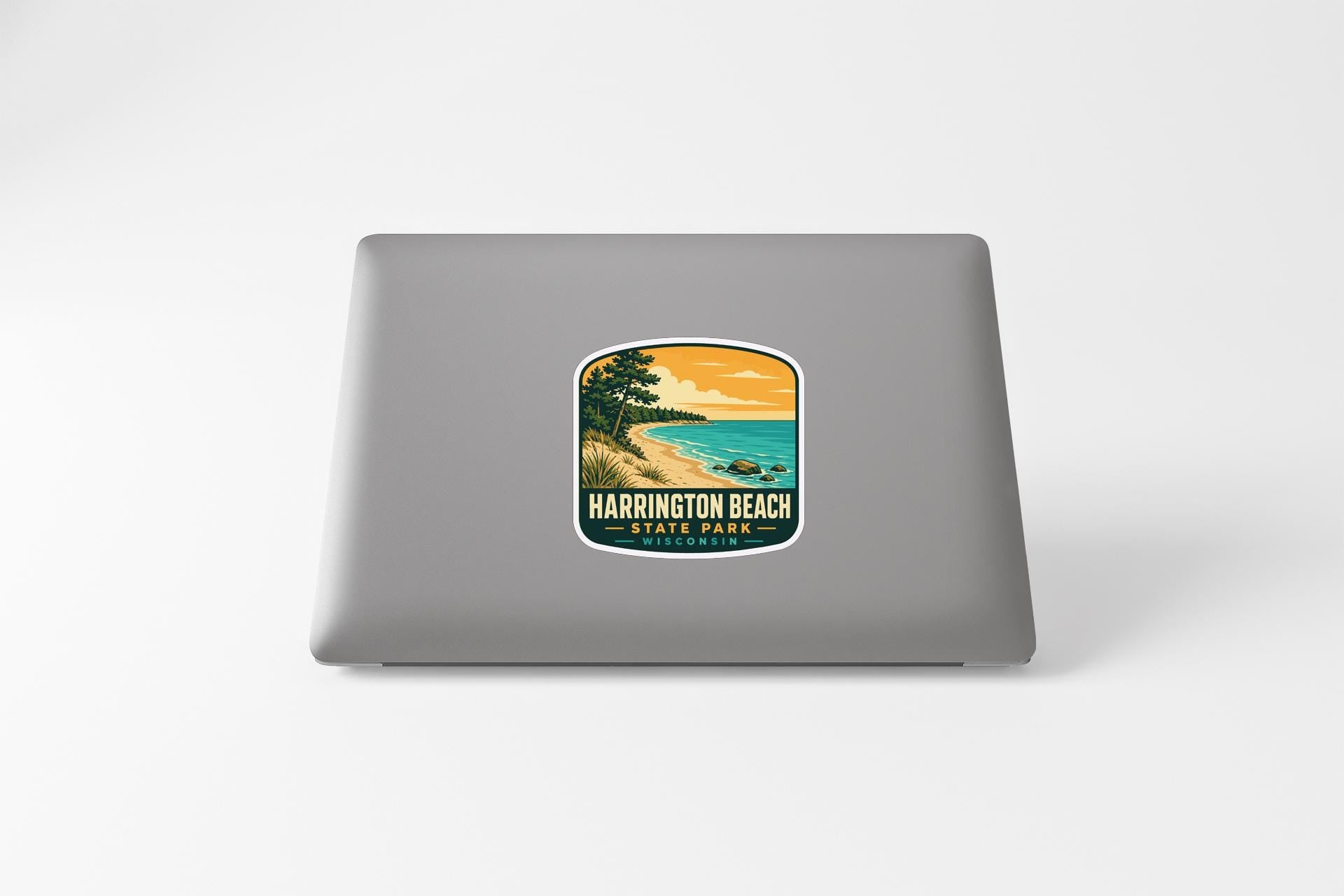 A sticker on the back of a laptop, depicting a scenic beach landscape with a sunset over the water.