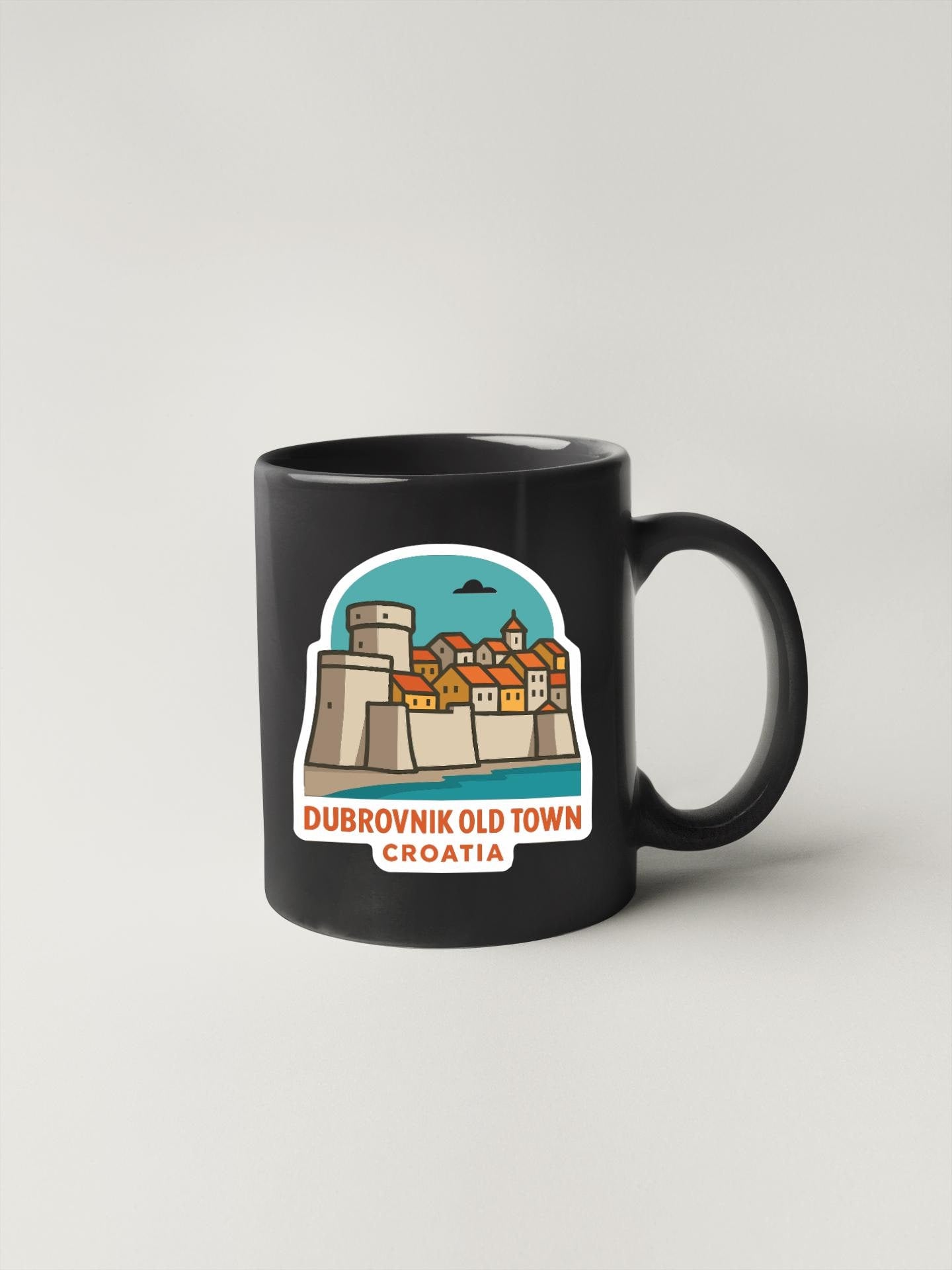 A black coffee mug with a sticker depicting Dubrovnik Old Town Croatia.