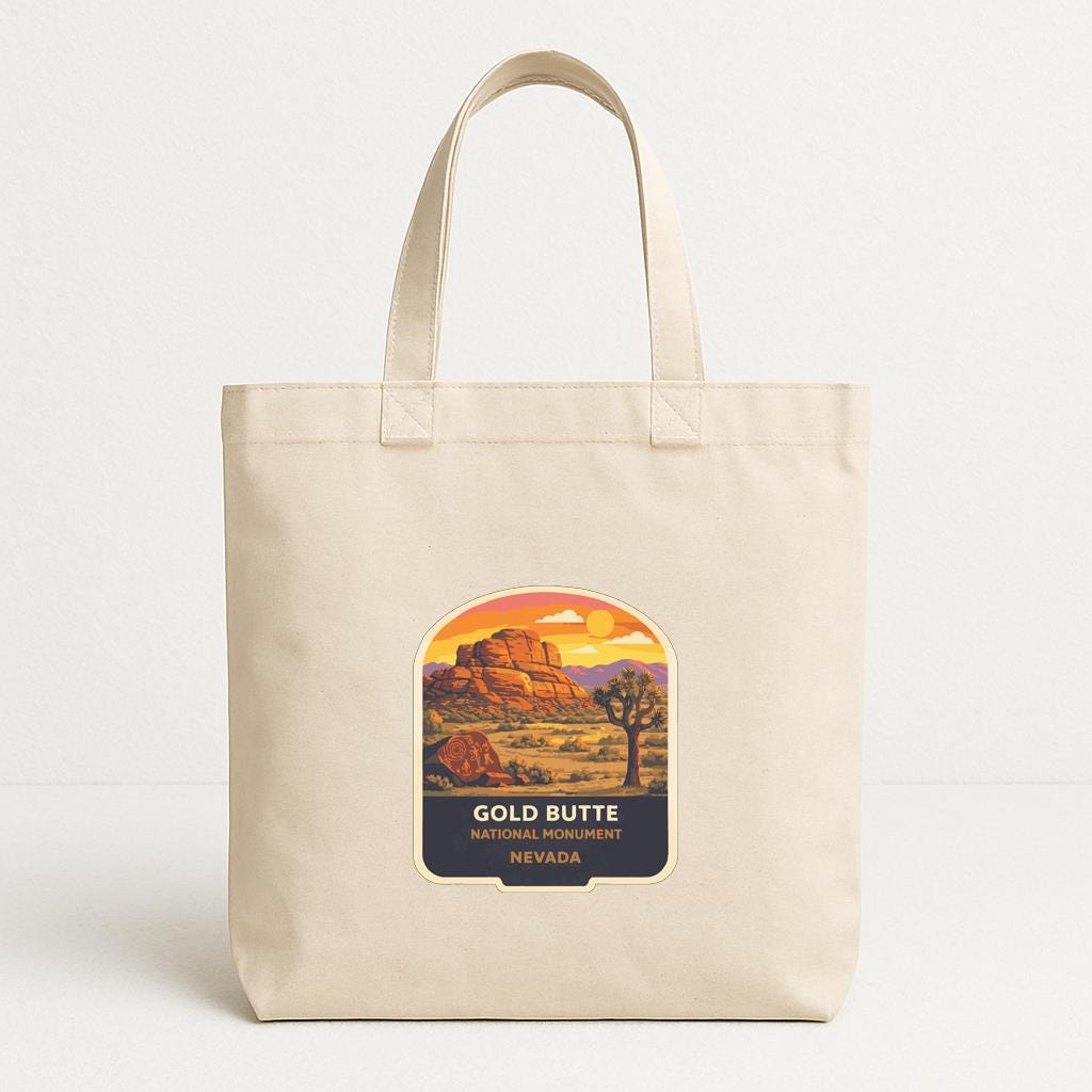 A beige tote bag with a graphic design depicting a desert landscape with a mountain and a sunset.