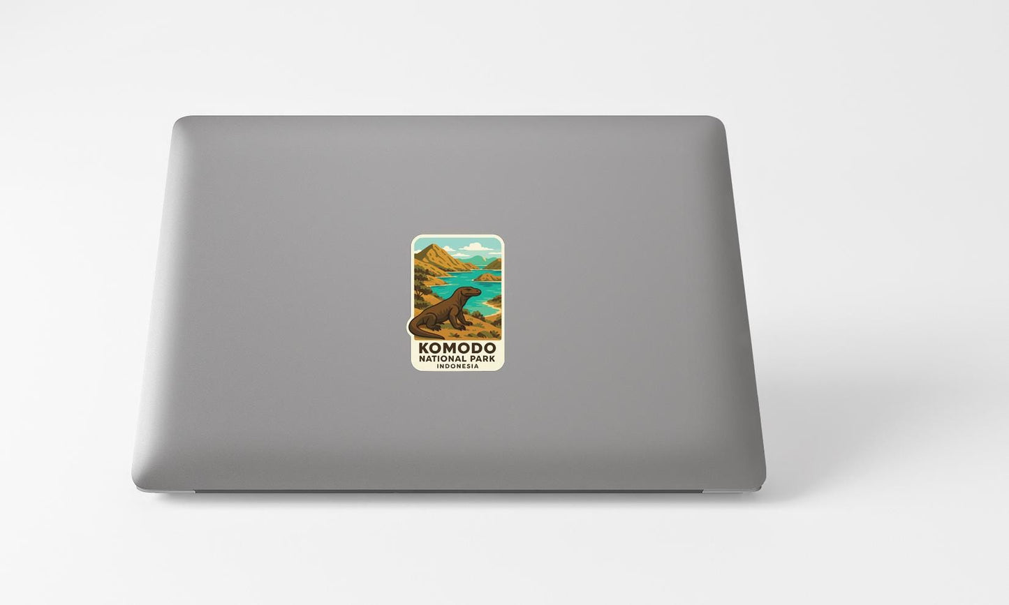 A sticker on the back of a laptop, depicting a scenic landscape with mountains, a lake, and a komodo dragon.
