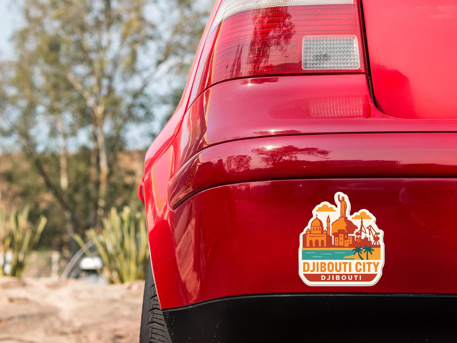 the rear end of a red car with a sticker on the trunk that says "DJIBOUTI CITY DJIBOUTI".