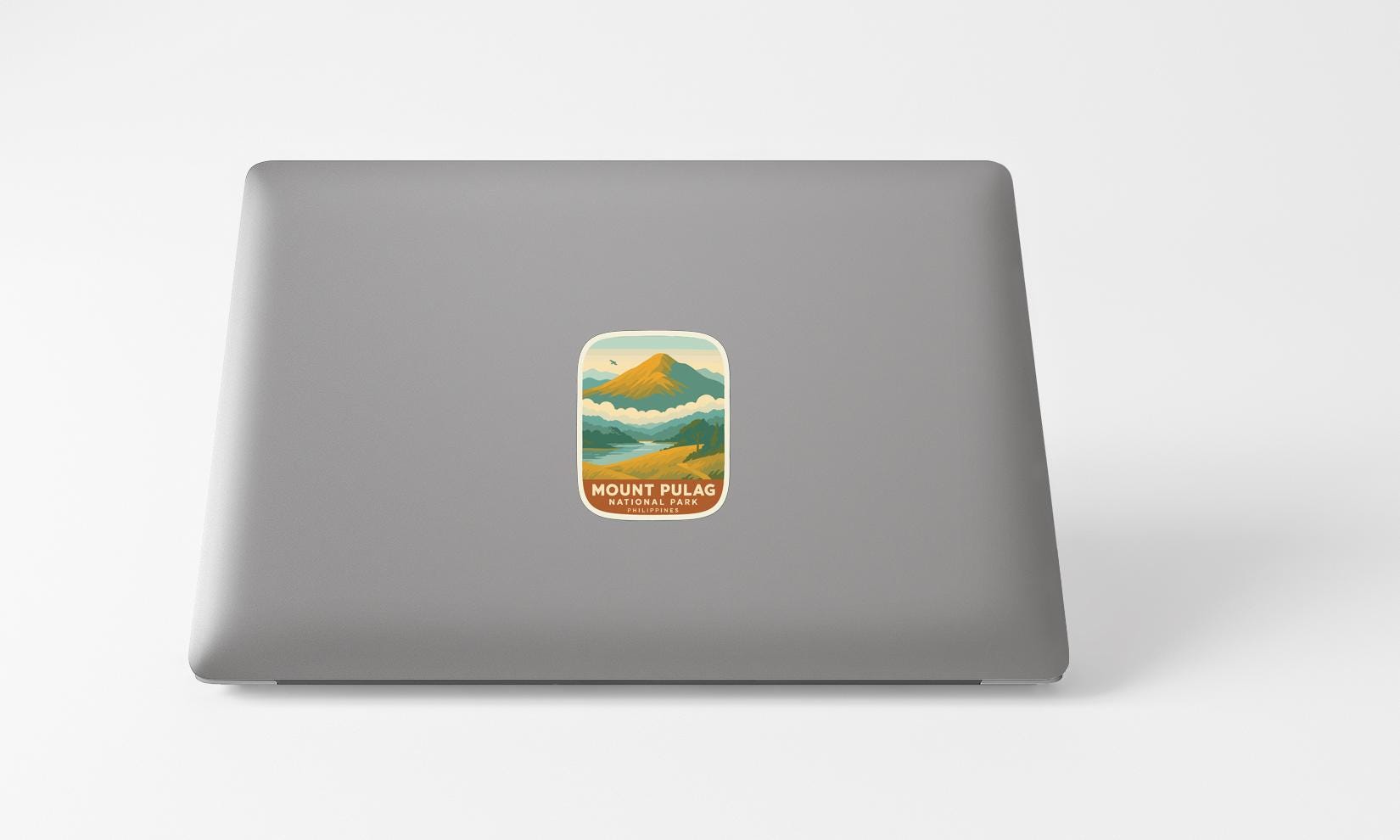 A sticker of a mountain landscape on the back of a laptop computer.