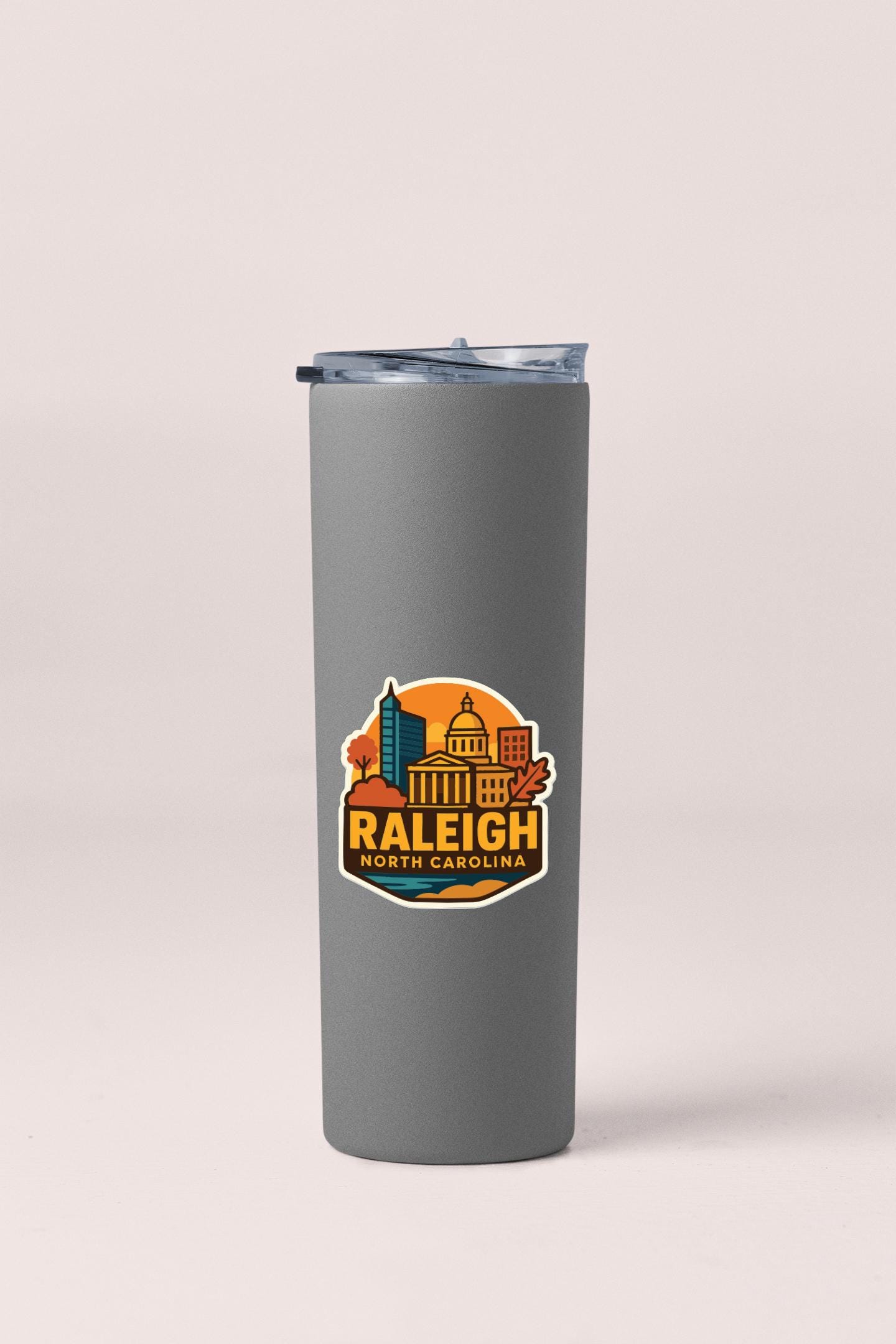 A gray insulated tumbler with a graphic design featuring the skyline of Raleigh, North Carolina.