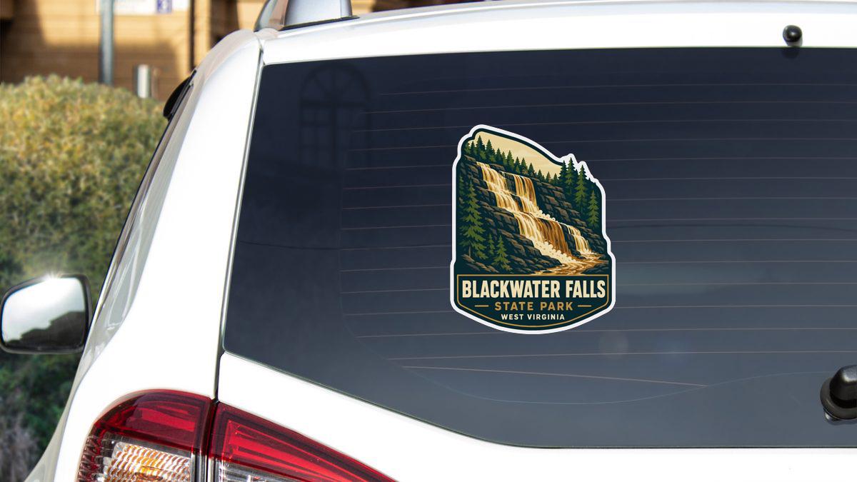 A sticker on the rear window of a white car, depicting a scenic waterfall surrounded by trees.