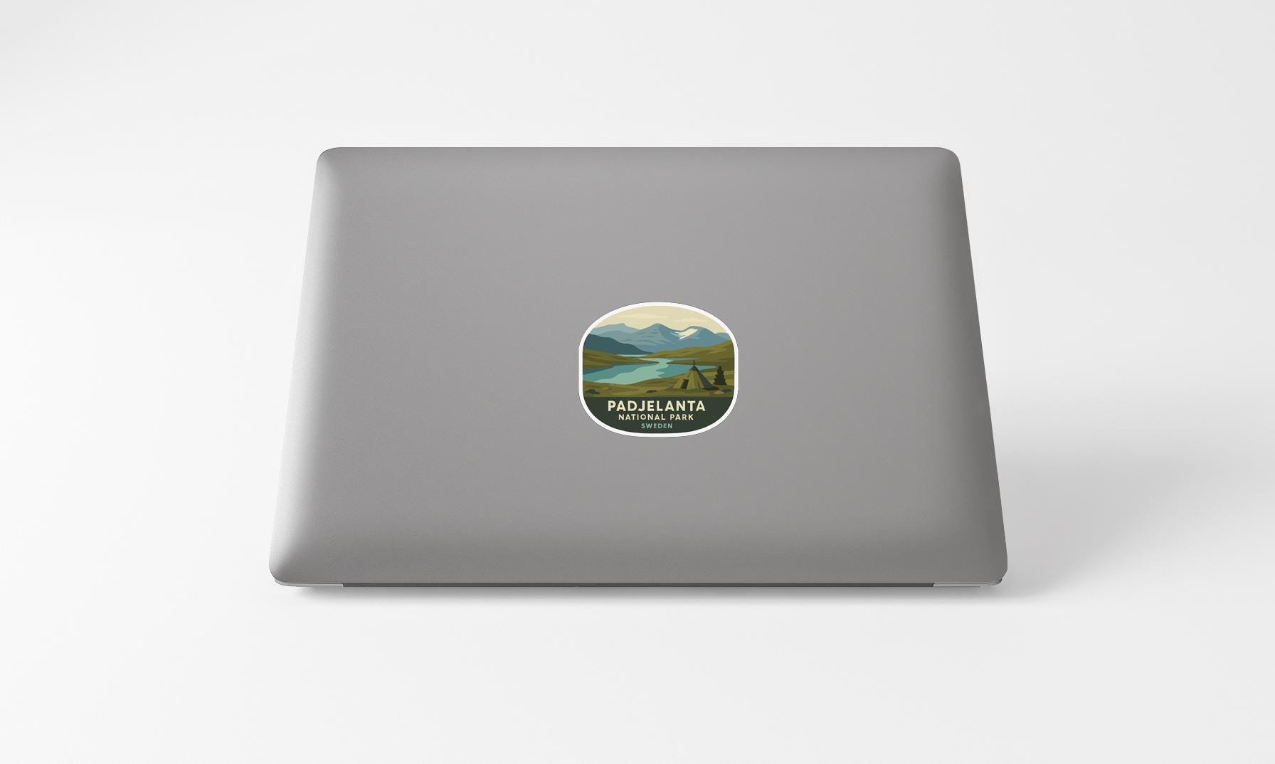 A sticker on the back of a laptop, depicting a scenic landscape with mountains and a lake.
