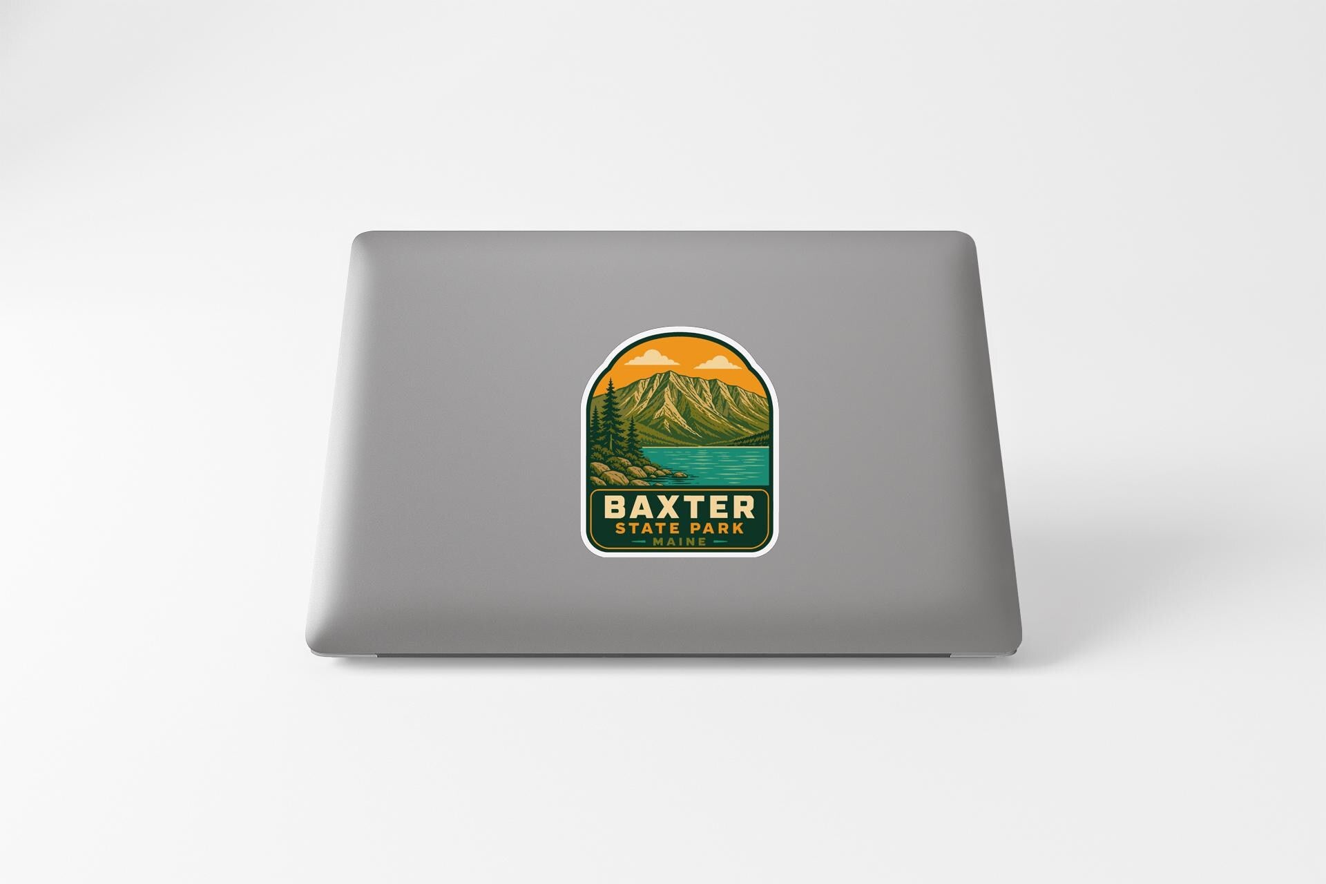 A sticker on the back of a laptop, depicting a scenic mountain landscape with a lake and mountains in the background.