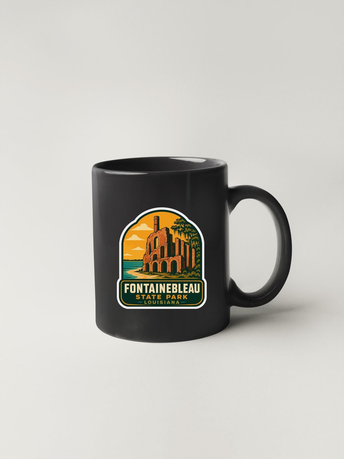 A black coffee mug with a graphic design depicting a castle or palace, along with the text "Fontainebleau State Park" printed on it.