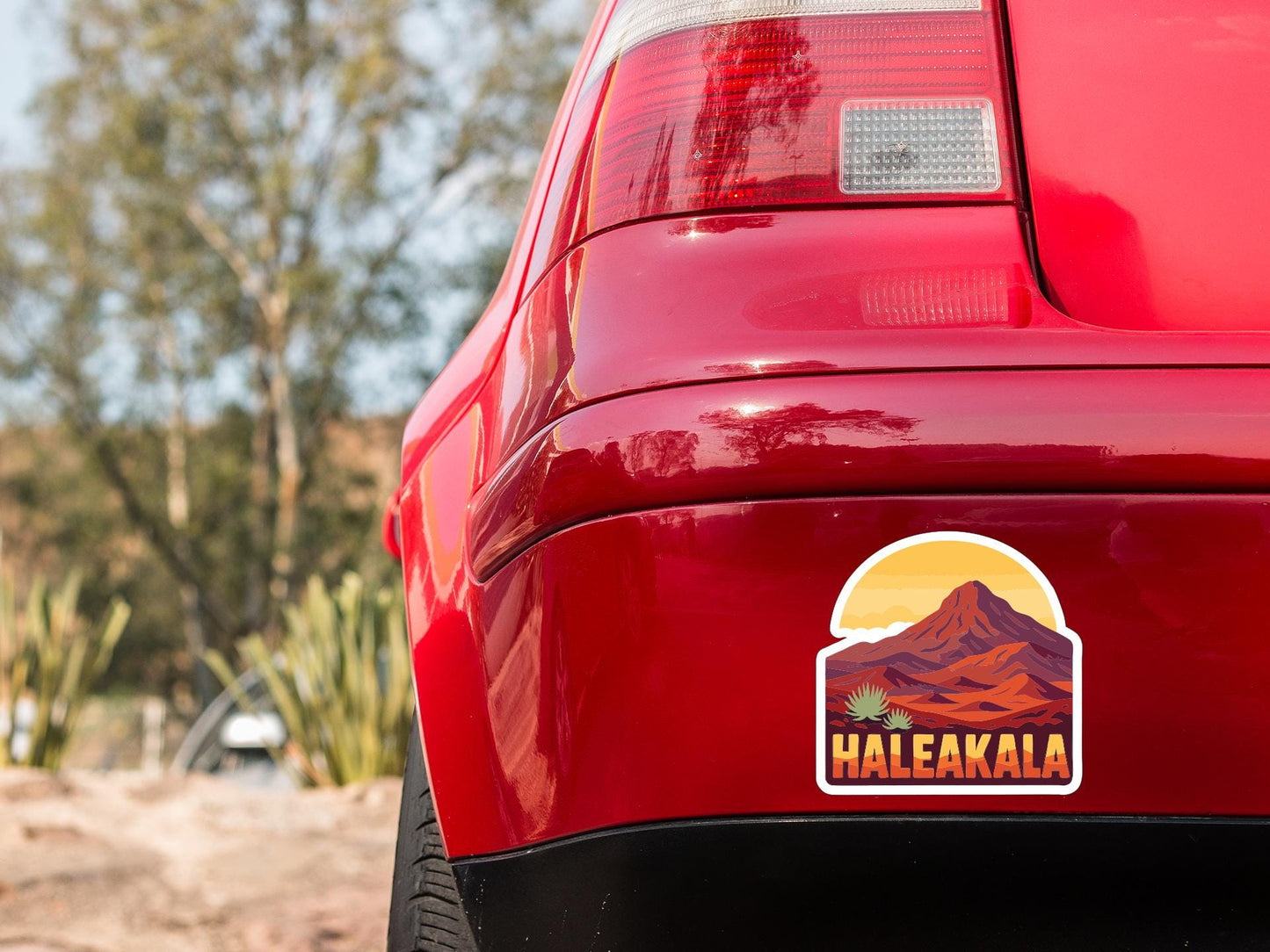 the rear end of a red car with a sticker on the trunk that says "Haleakala".