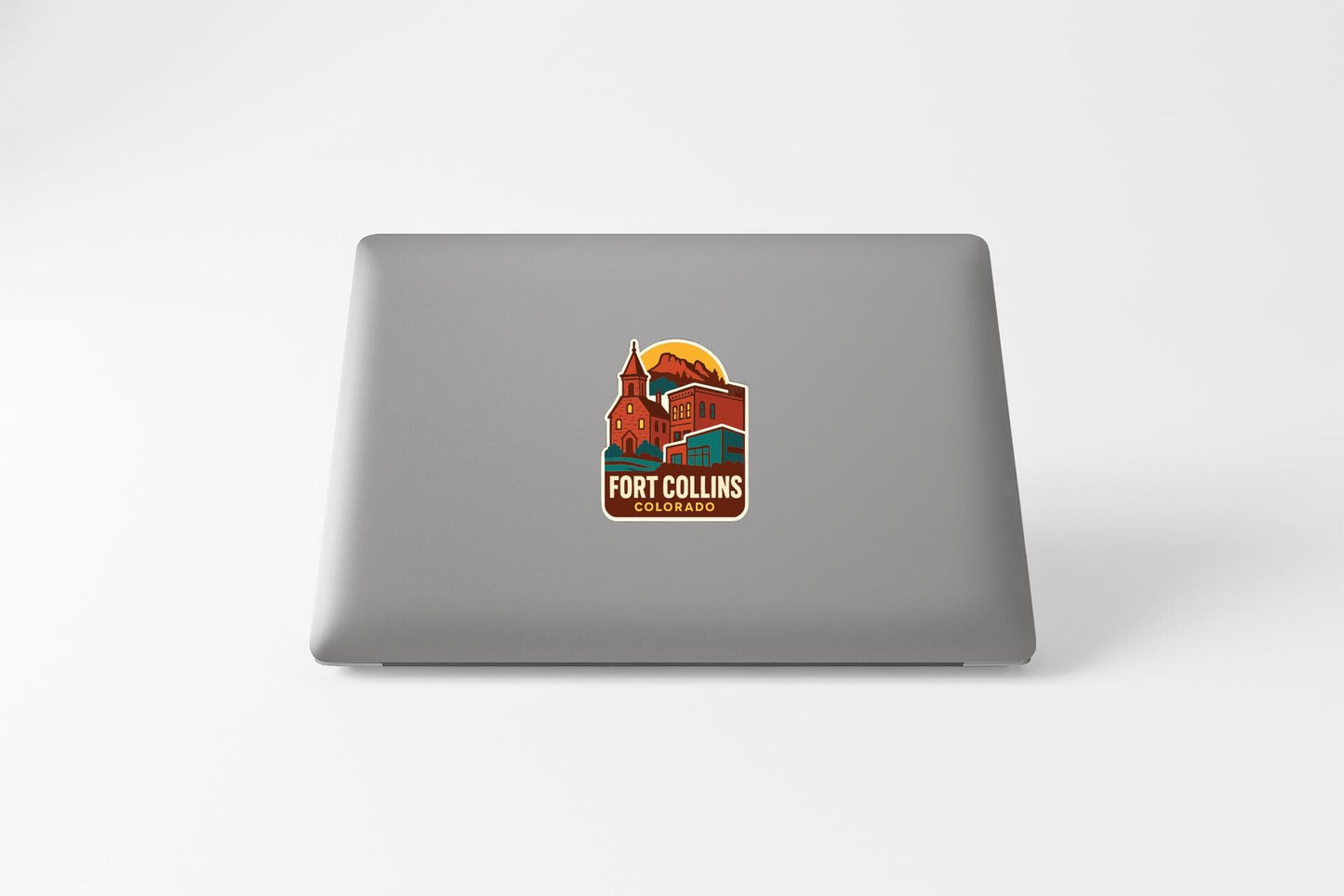 a sticker with a colorful illustration of Fort Collins, Colorado, on the back of a laptop.
