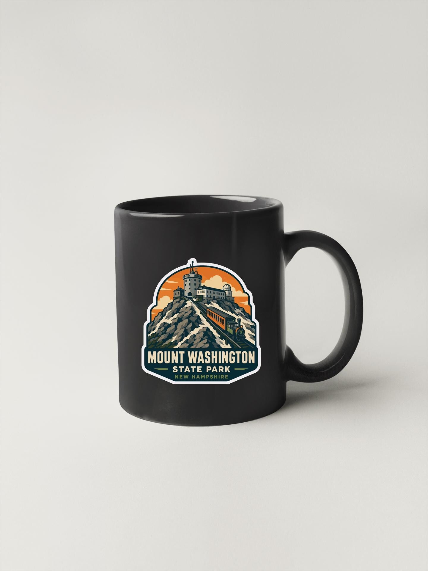 A black coffee mug with a graphic design depicting Mount Washington State Park.