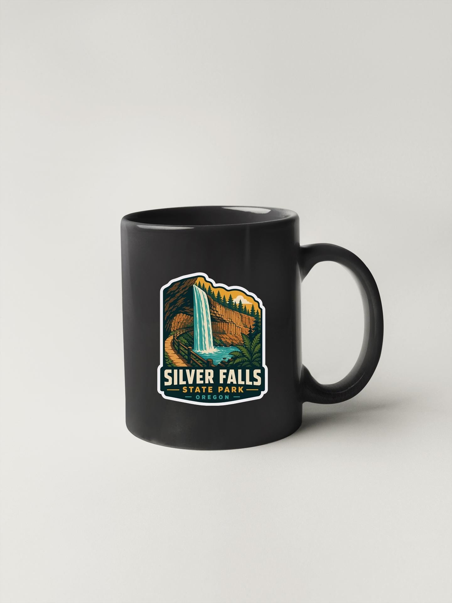 A black coffee mug with a graphic design depicting a waterfall and the text "Silver Falls State Park" printed on it.