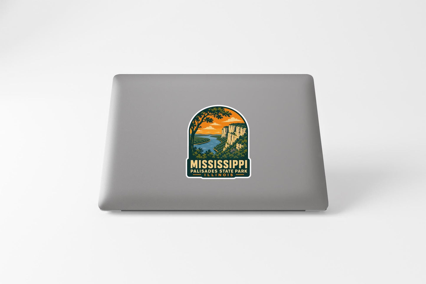 A sticker on the back of a laptop, depicting a scenic landscape with a river and mountains.