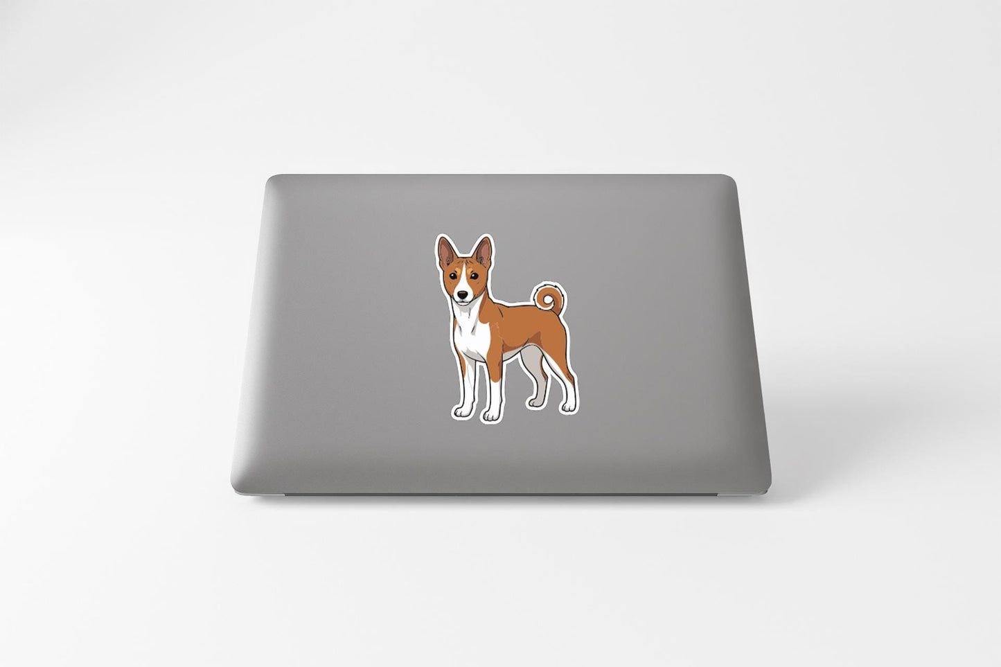 A sticker of a dog, specifically a Basenji, is placed on the back of a laptop computer.
