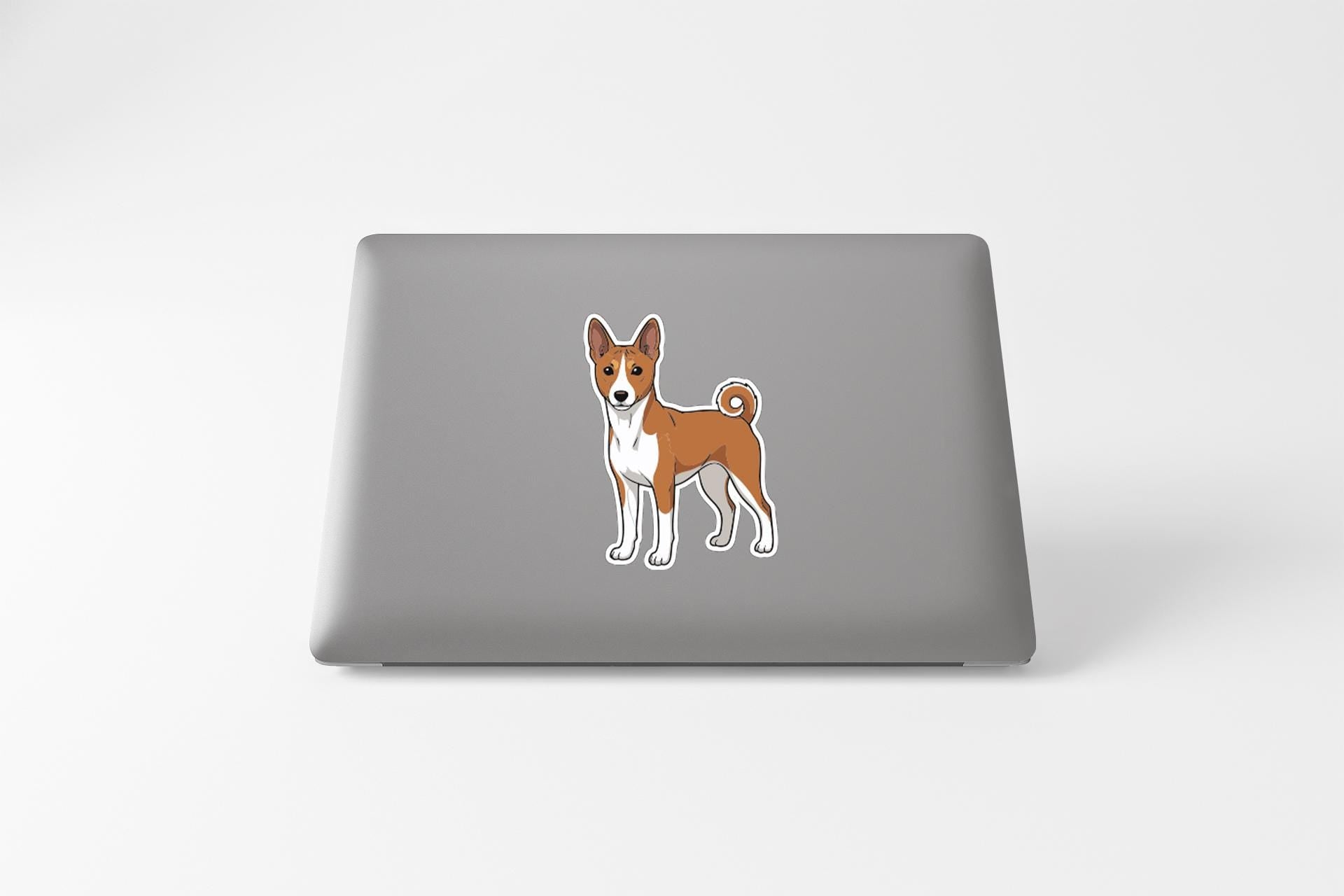 A sticker of a dog, specifically a Basenji, is placed on the back of a laptop computer.