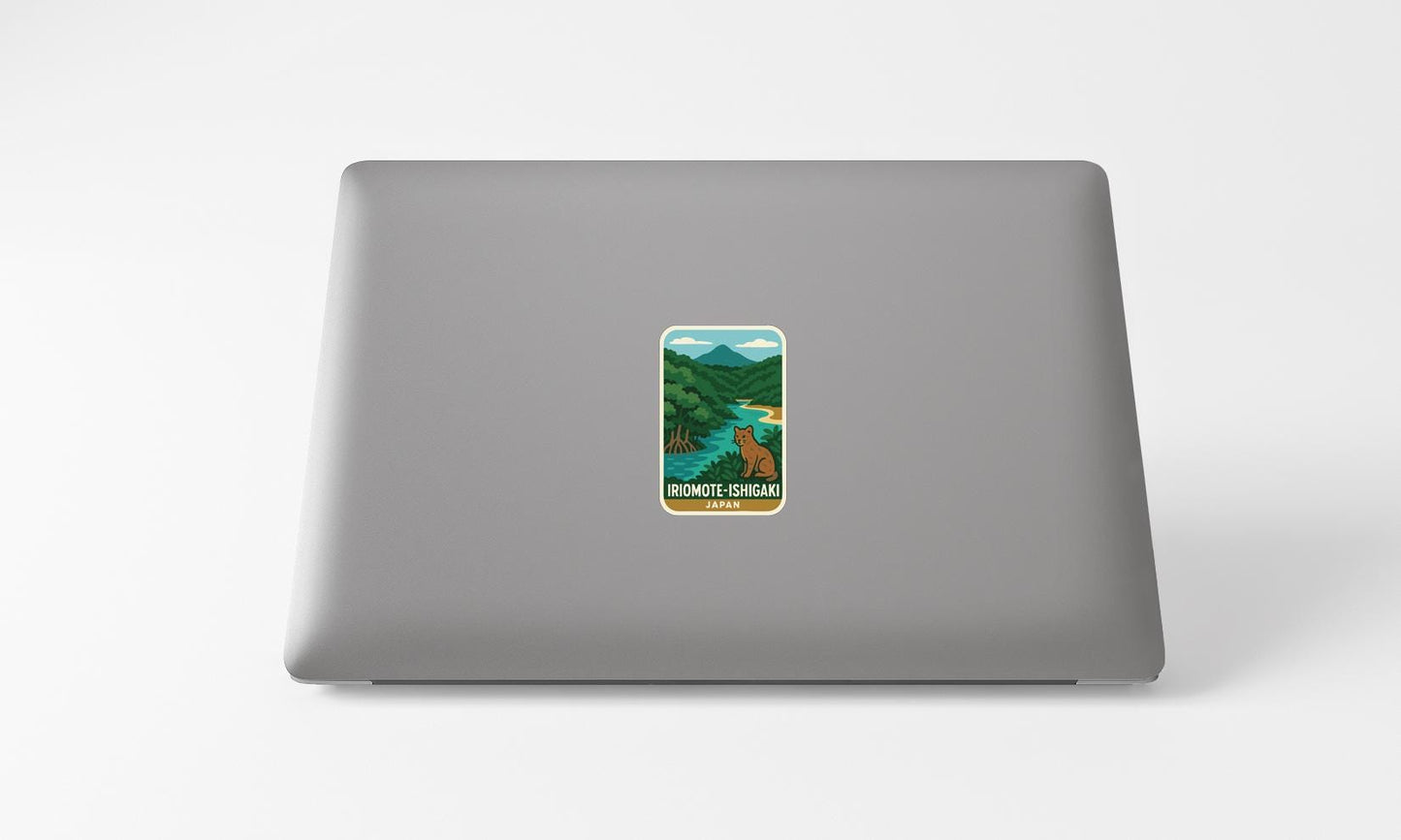 A sticker depicting a scenic landscape with mountains, a river, and a bear is affixed to the back of a laptop computer.