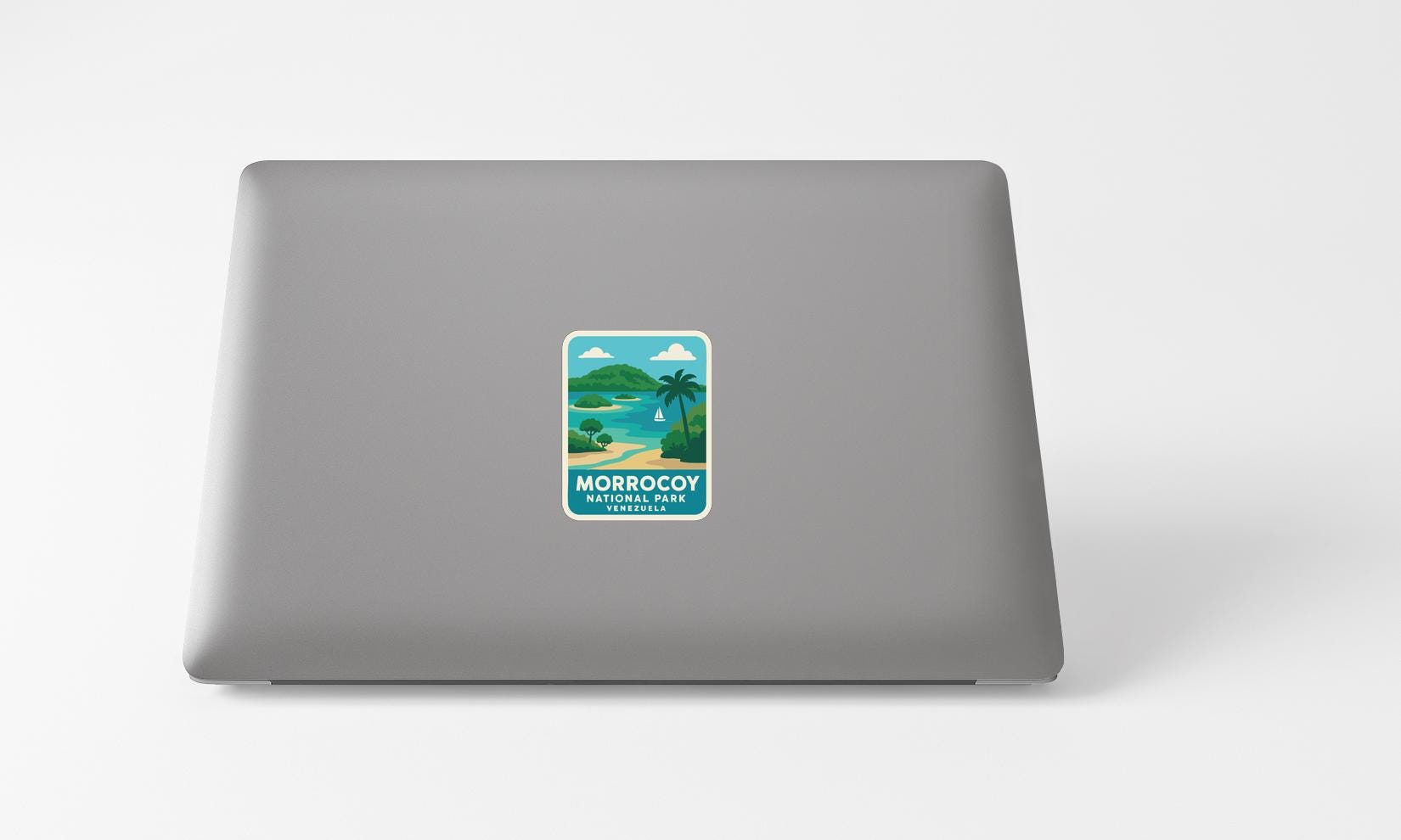 A sticker on the back of a laptop displaying a tropical beach scene with palm trees and a body of water.