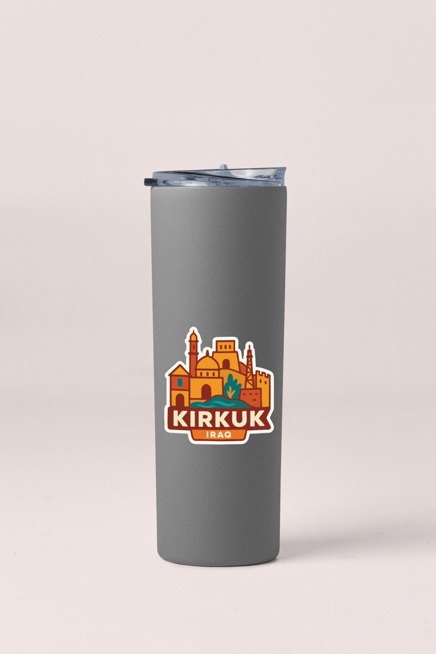 A gray insulated tumbler with a lid and a sticker featuring an illustration of a city skyline.