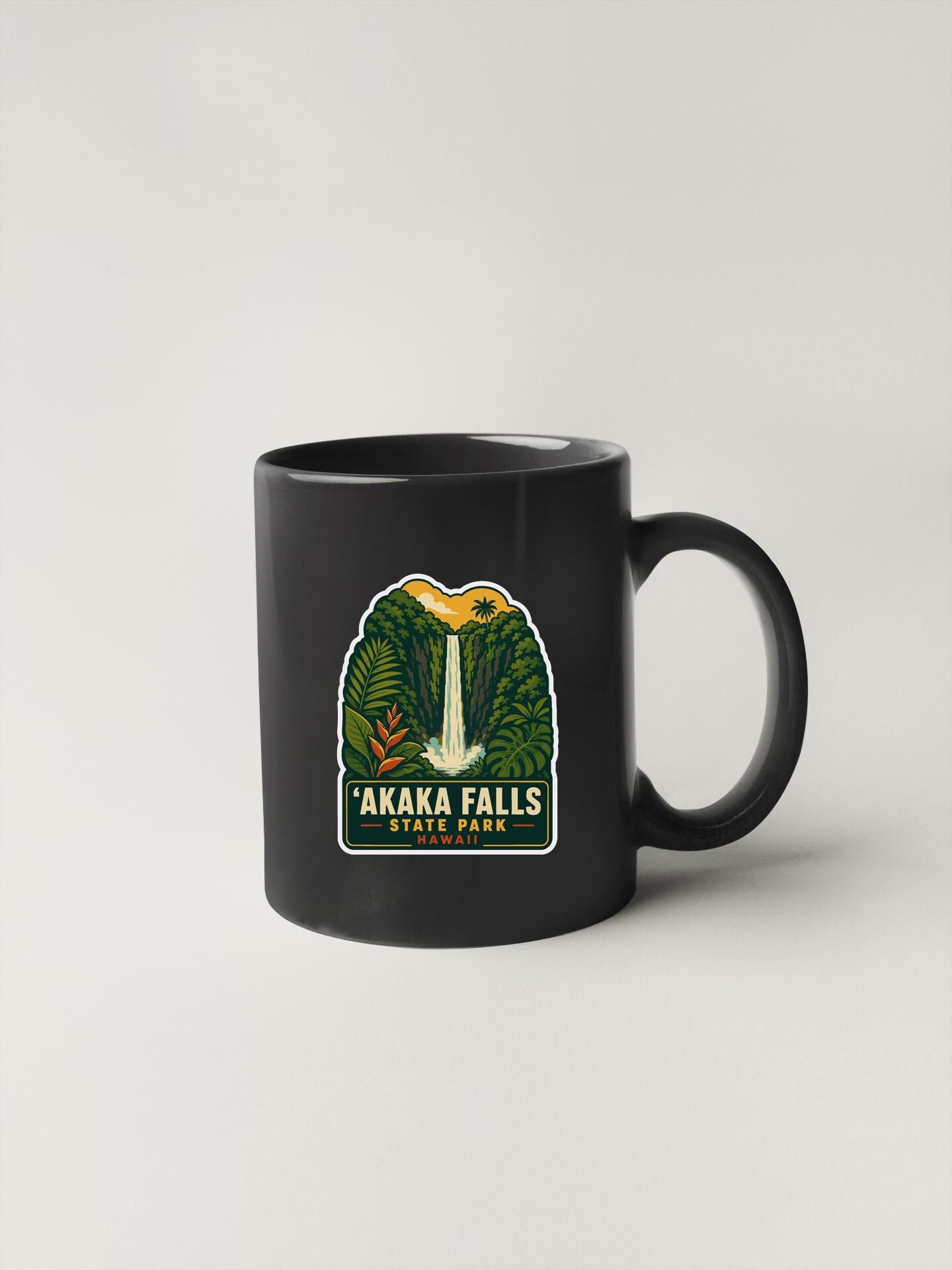A black coffee mug with a graphic design featuring a waterfall and tropical foliage.