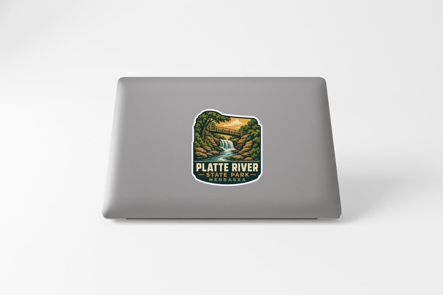 a sticker on a laptop that displays a scenic landscape with a waterfall and a forest.