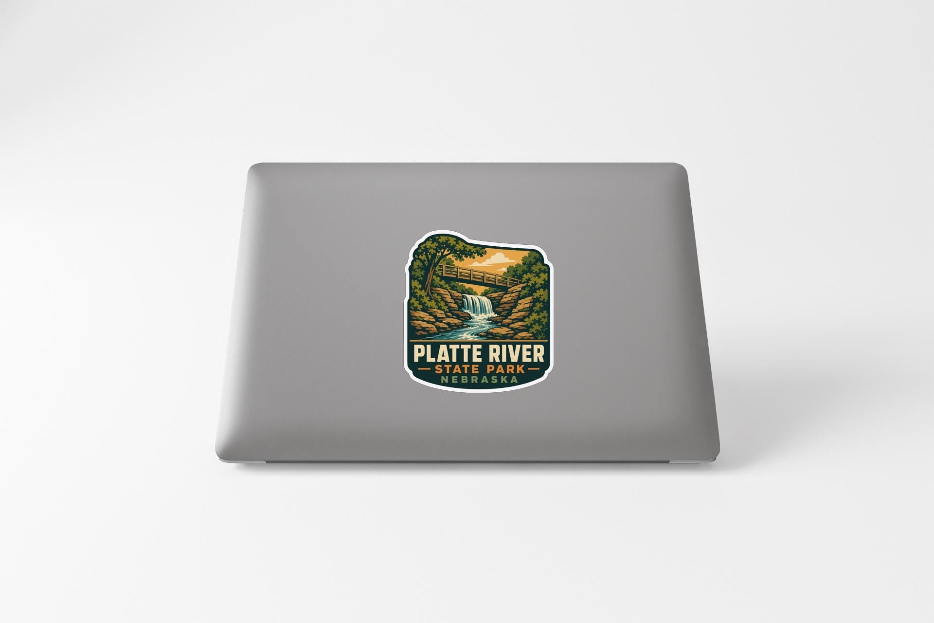 a sticker on a laptop that displays a scenic landscape with a waterfall and a forest.
