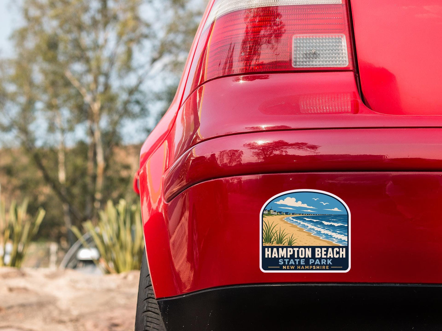 the rear end of a red car with a sticker on the back window that says "Hampton Beach State Park New Hampshire".
