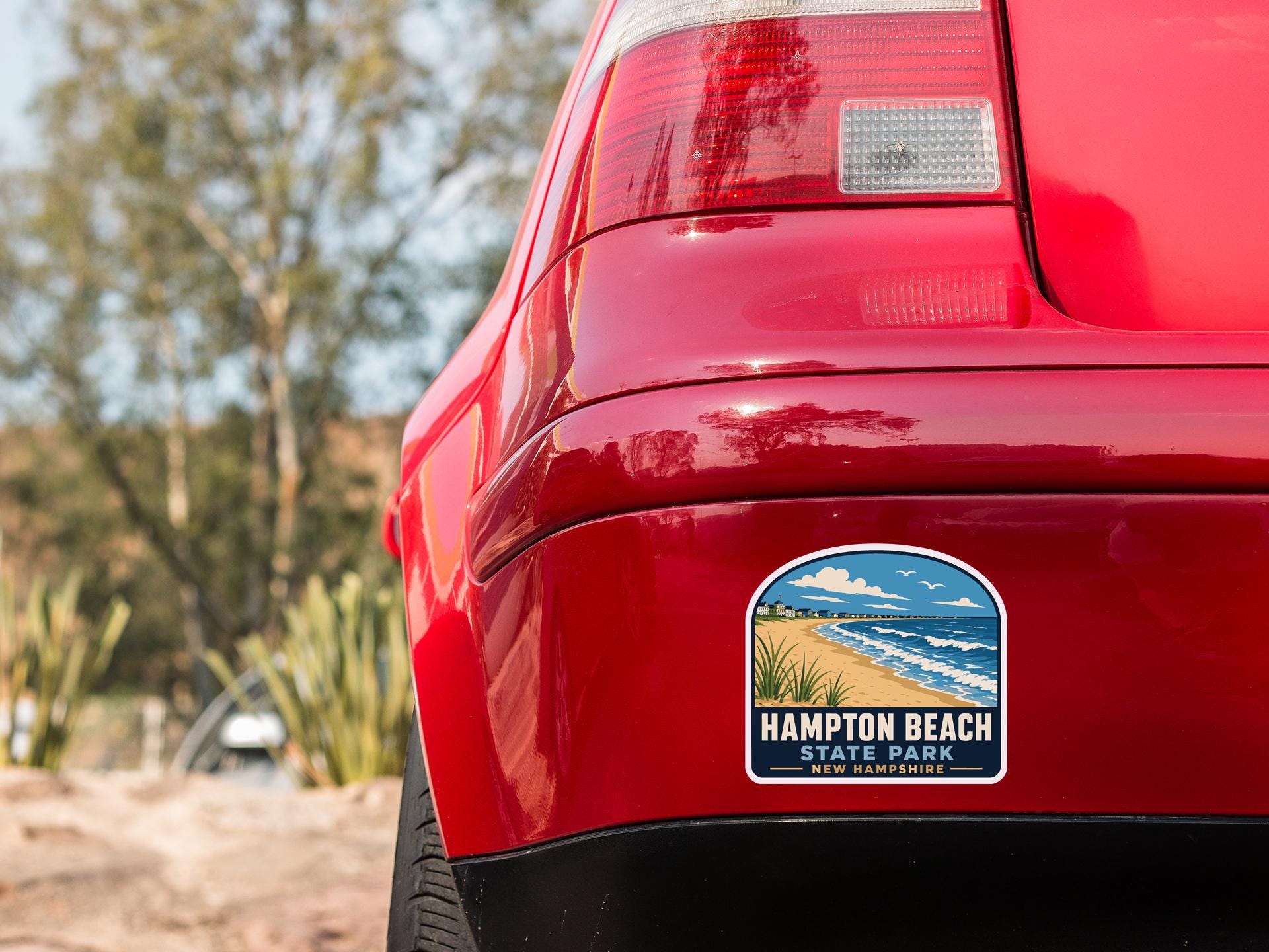 the rear end of a red car with a sticker on the back window that says "Hampton Beach State Park New Hampshire".