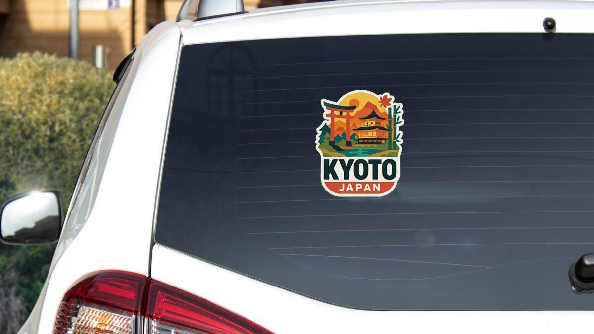 A sticker on the rear window of a white car, depicting a scenic view of Kyoto, Japan.
