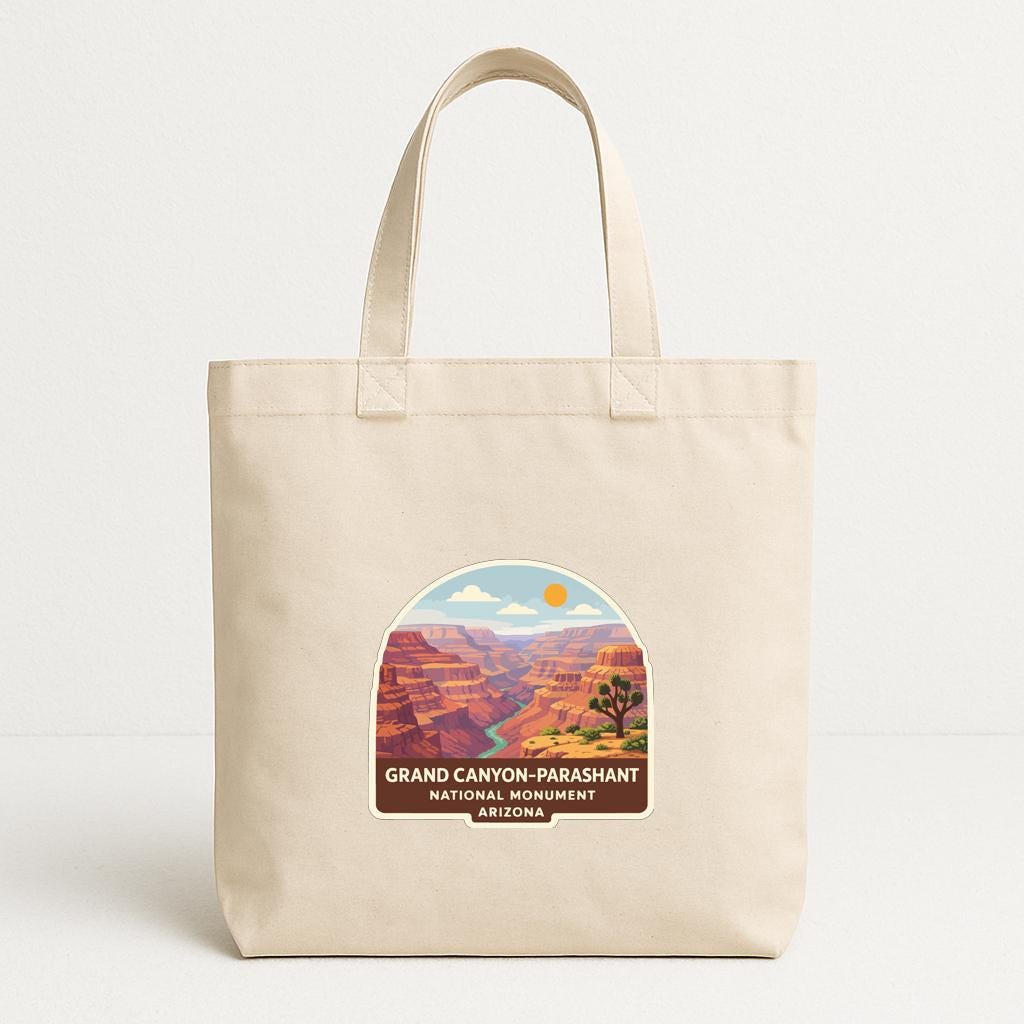 A beige tote bag with a printed label that says "GRAND CANYON-PARASHANT NATIONAL MONUMENT ARIZONA" and features an illustration of the Grand Canyon.