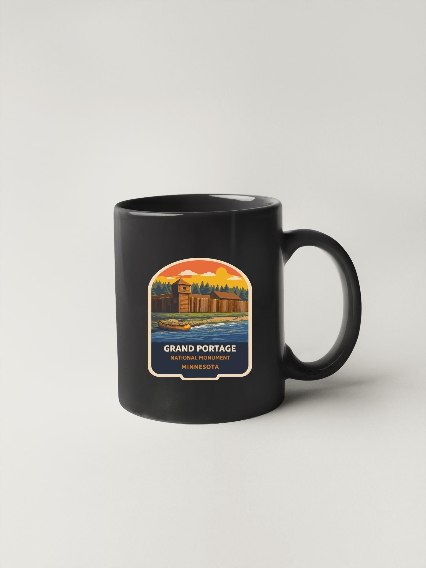 A black coffee mug with a label that says "GRAND PORTAGE NATIONAL MONUMENT, MINNESOTA".