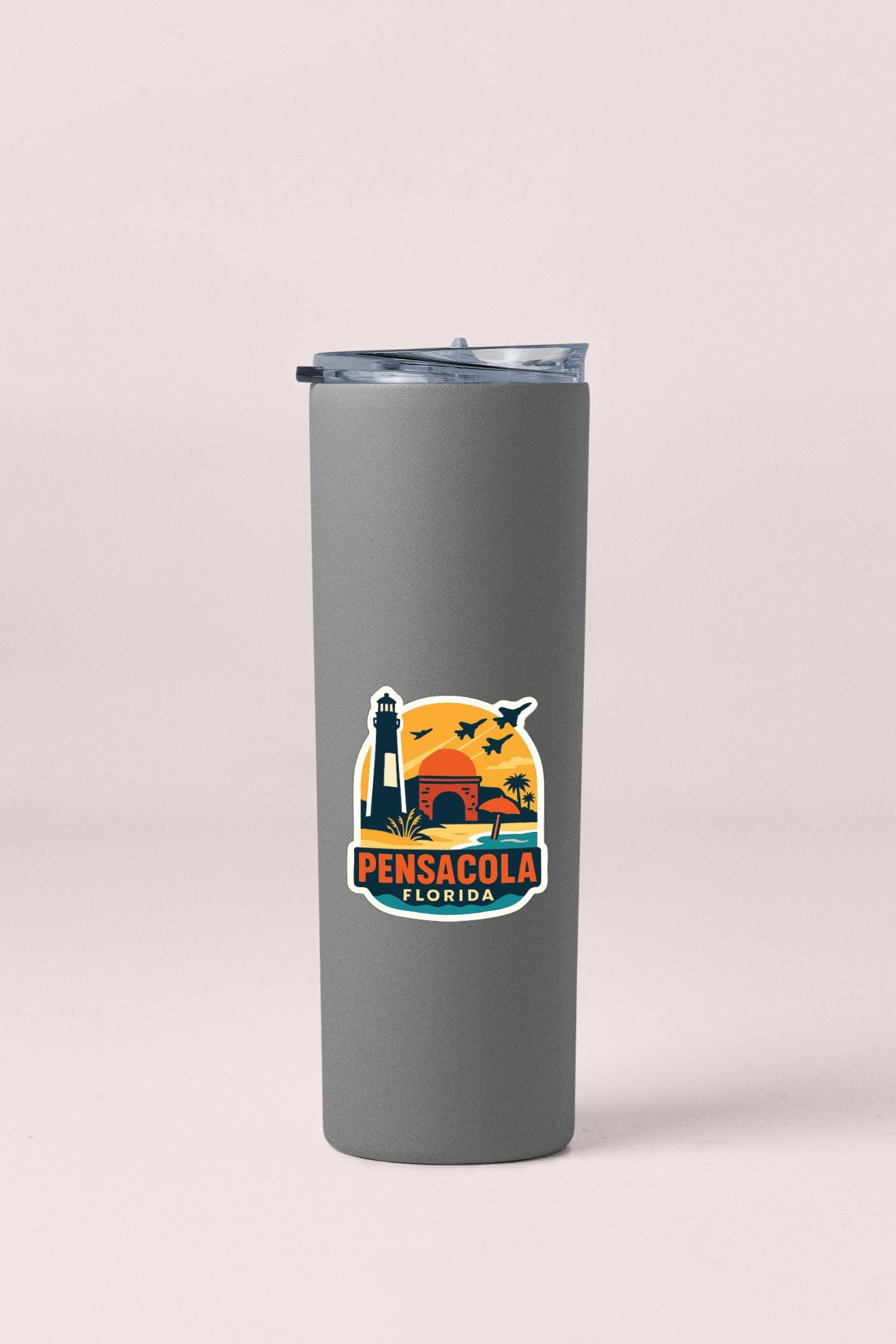A gray insulated tumbler with a sticker depicting a lighthouse and a sunset in Pensacola, Florida.