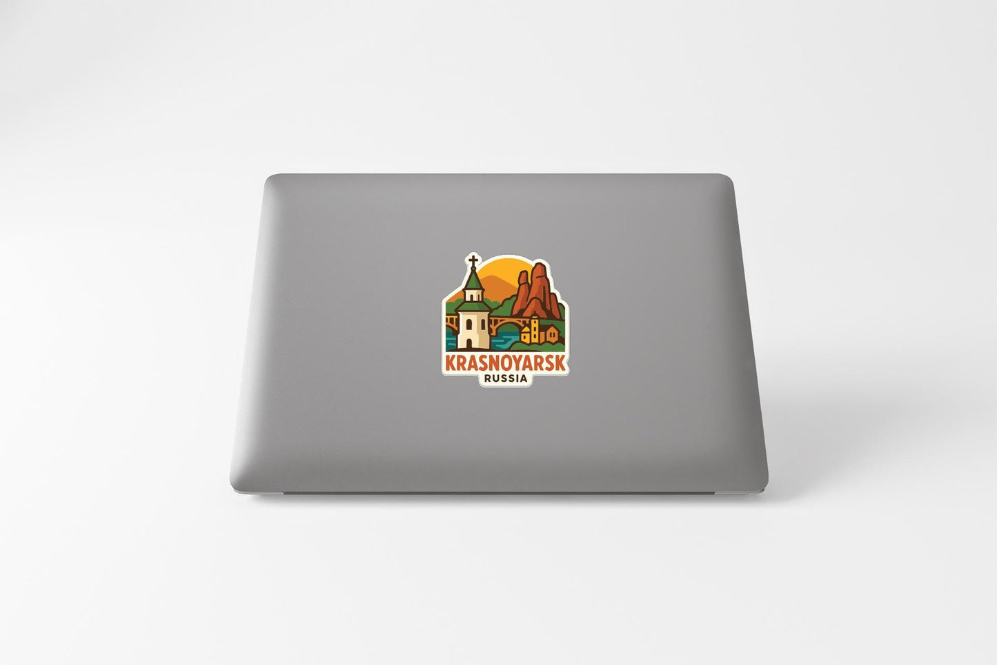 a sticker with a graphic of a landmark, specifically the Krasnoyarsk, Russia, on the back of a laptop.