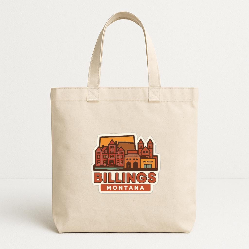 A beige tote bag with a graphic design depicting a cityscape and the text "BILLINGS MONTANA" printed on it.