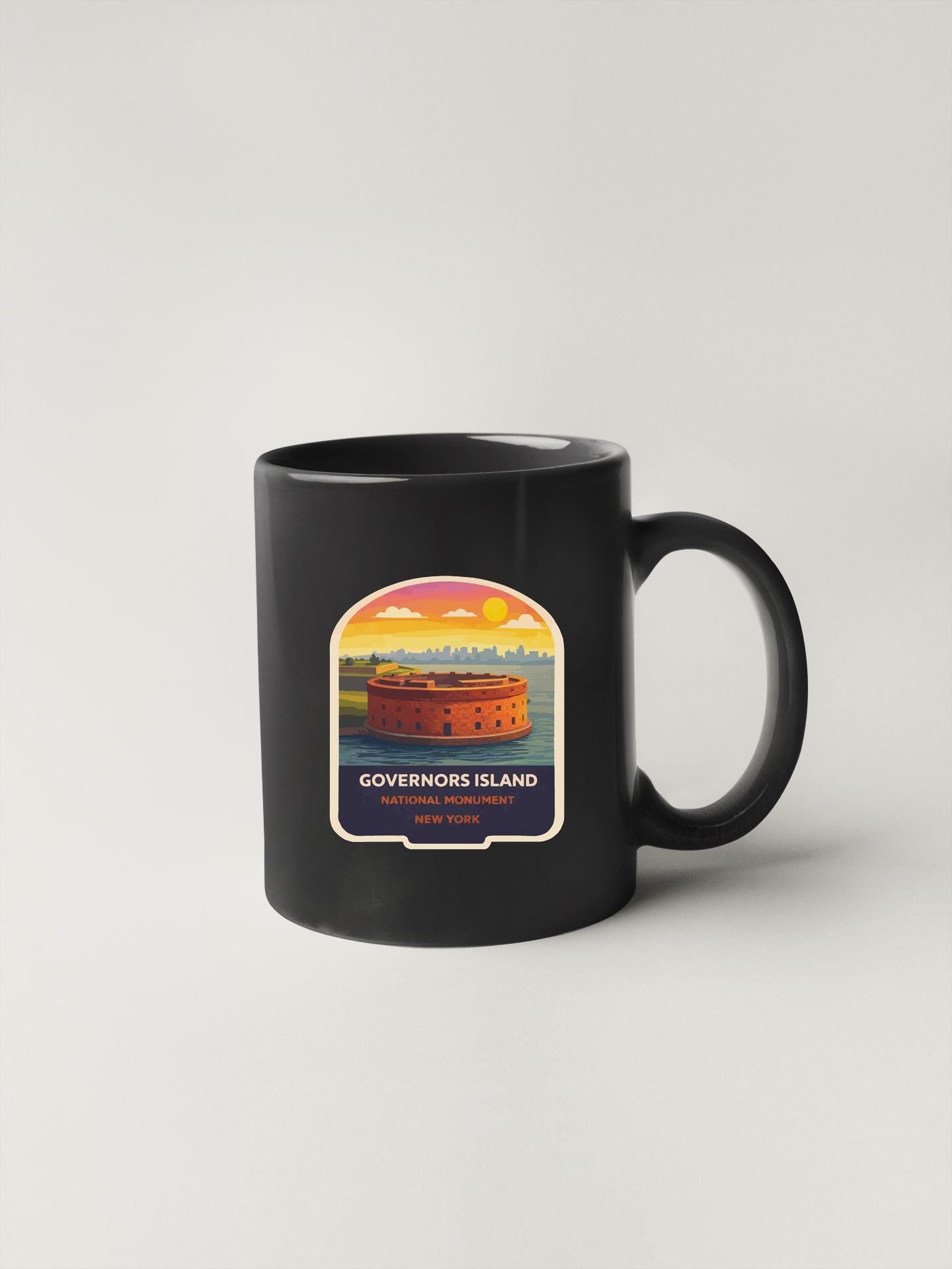 A black coffee mug with a label depicting the Governor's Island in New York.