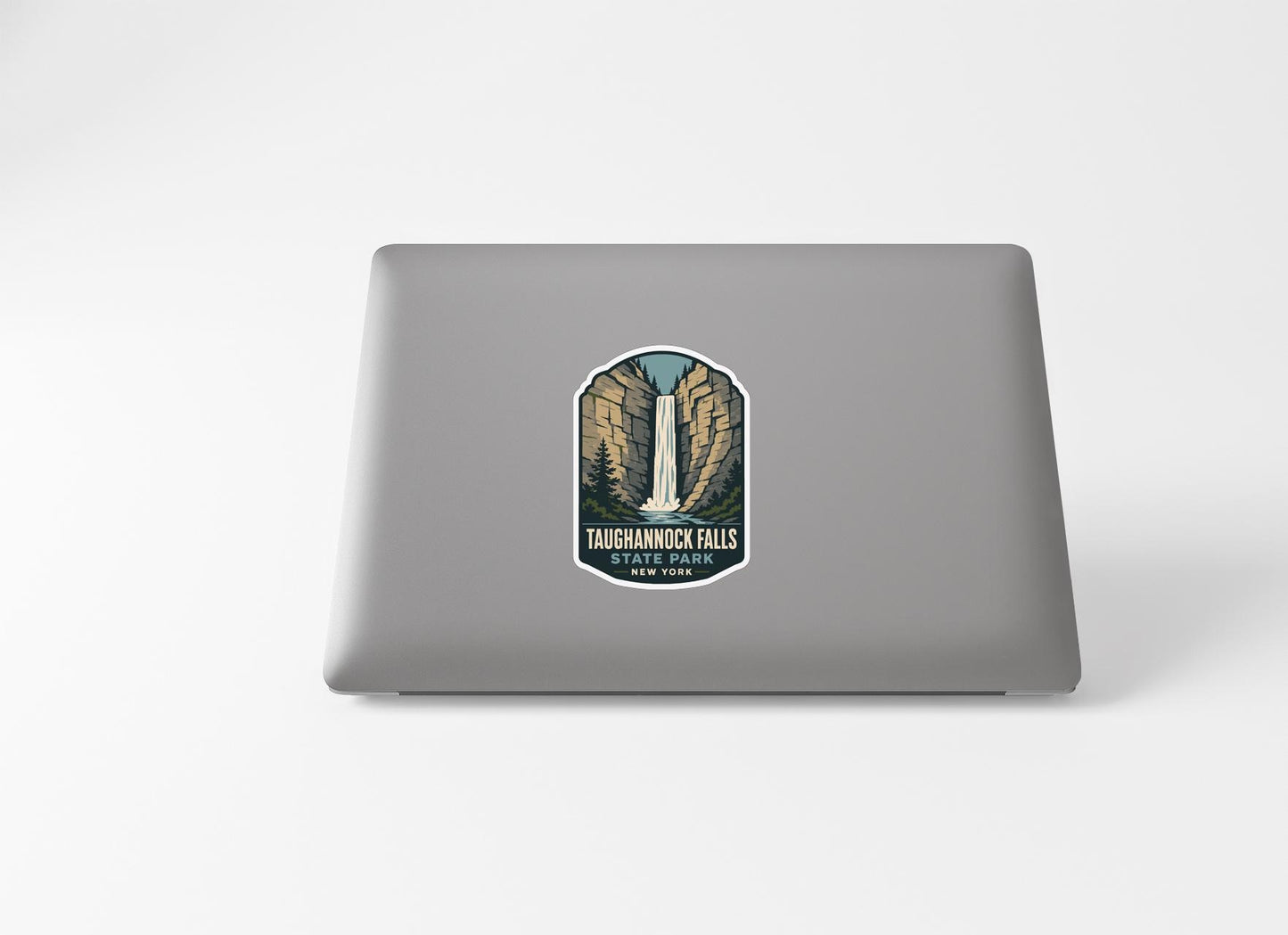 A sticker on the back of a laptop, depicting a waterfall surrounded by mountains.