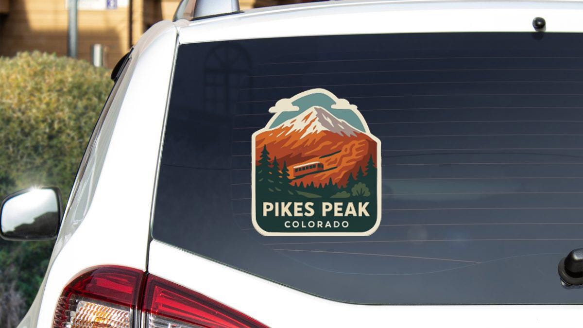 a sticker on the rear window of a white car that says "Pikes Peak, Colorado".